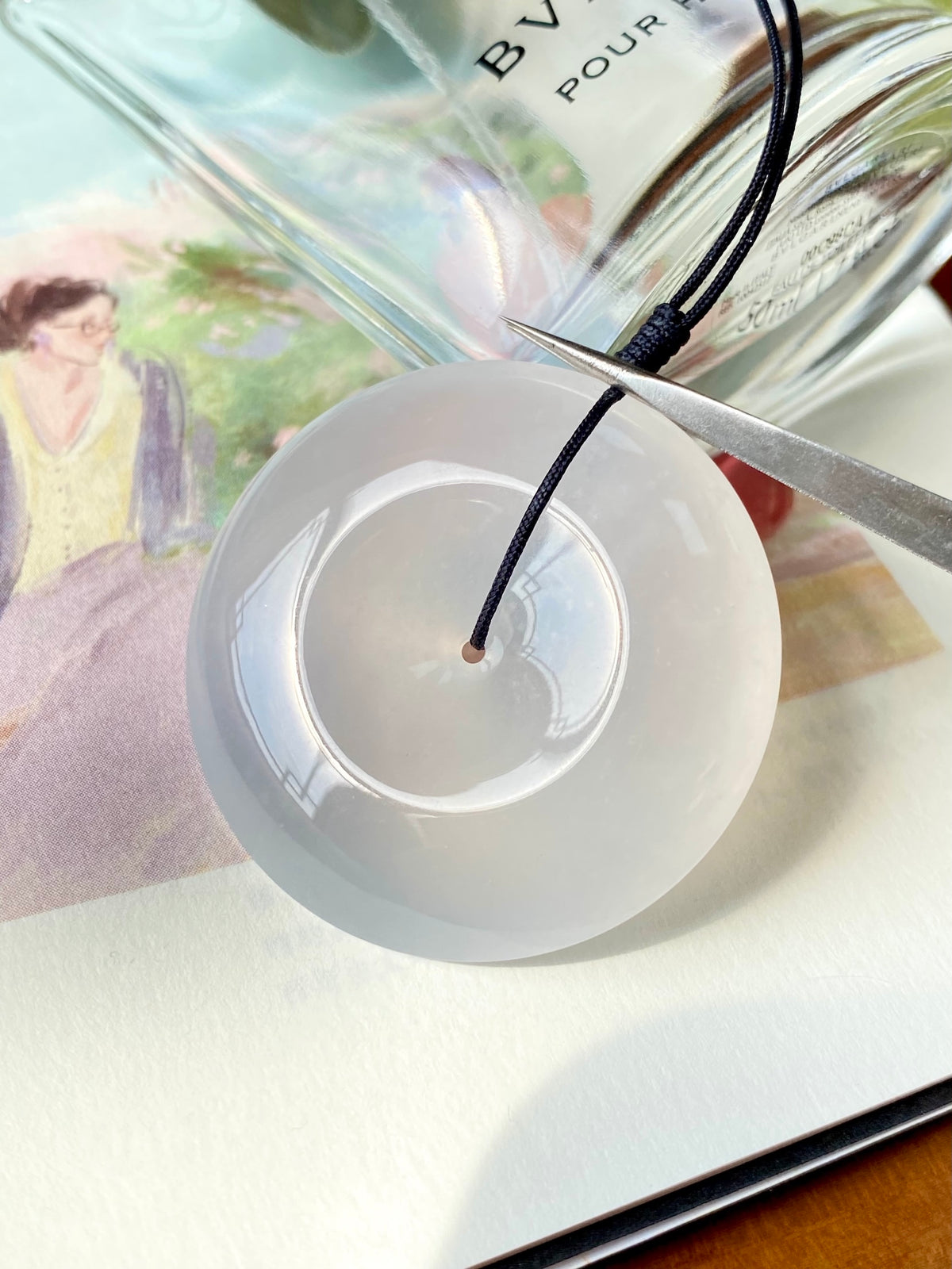 Icy white jadeite donut with black cord and silver tool tip