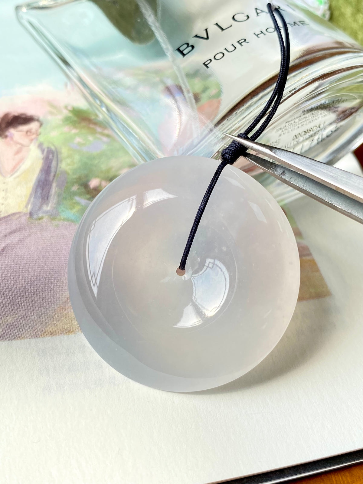 Icy white jadeite donut with black drawstring cord loop