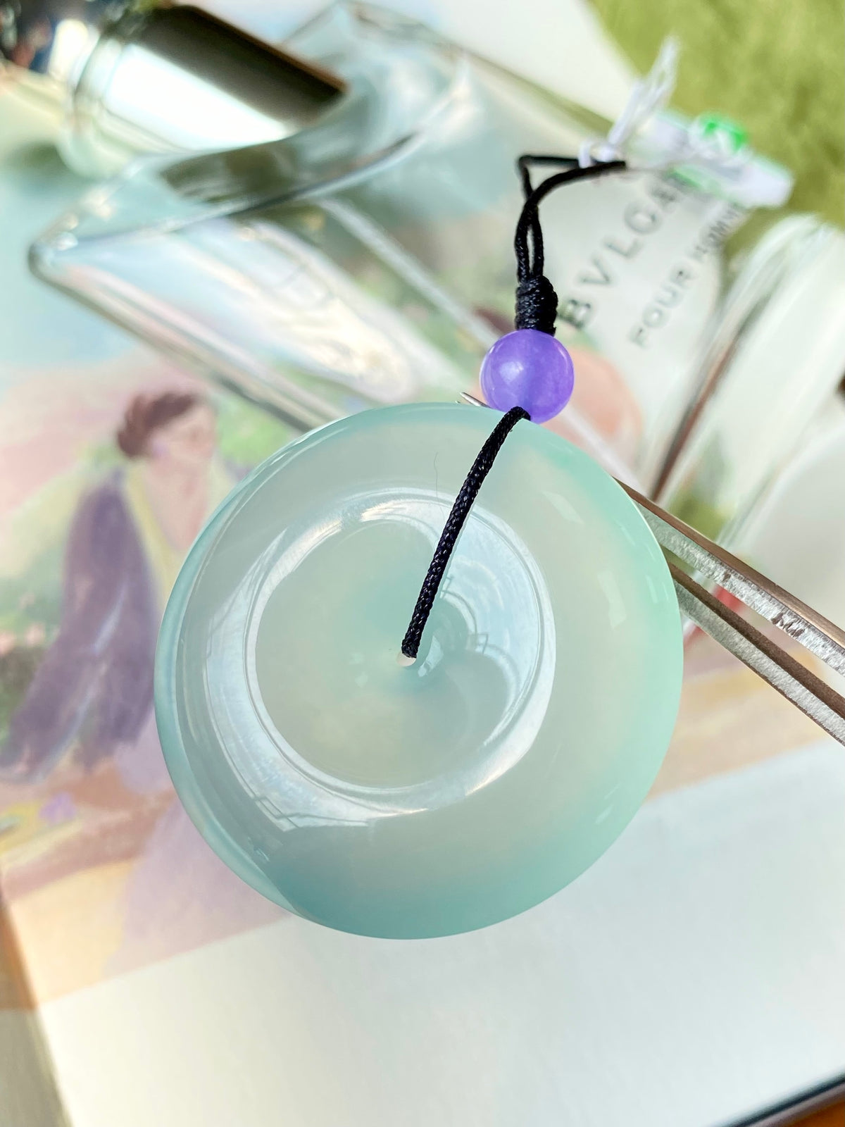 Mint green jade disc pendant with black cord and small purple bead top