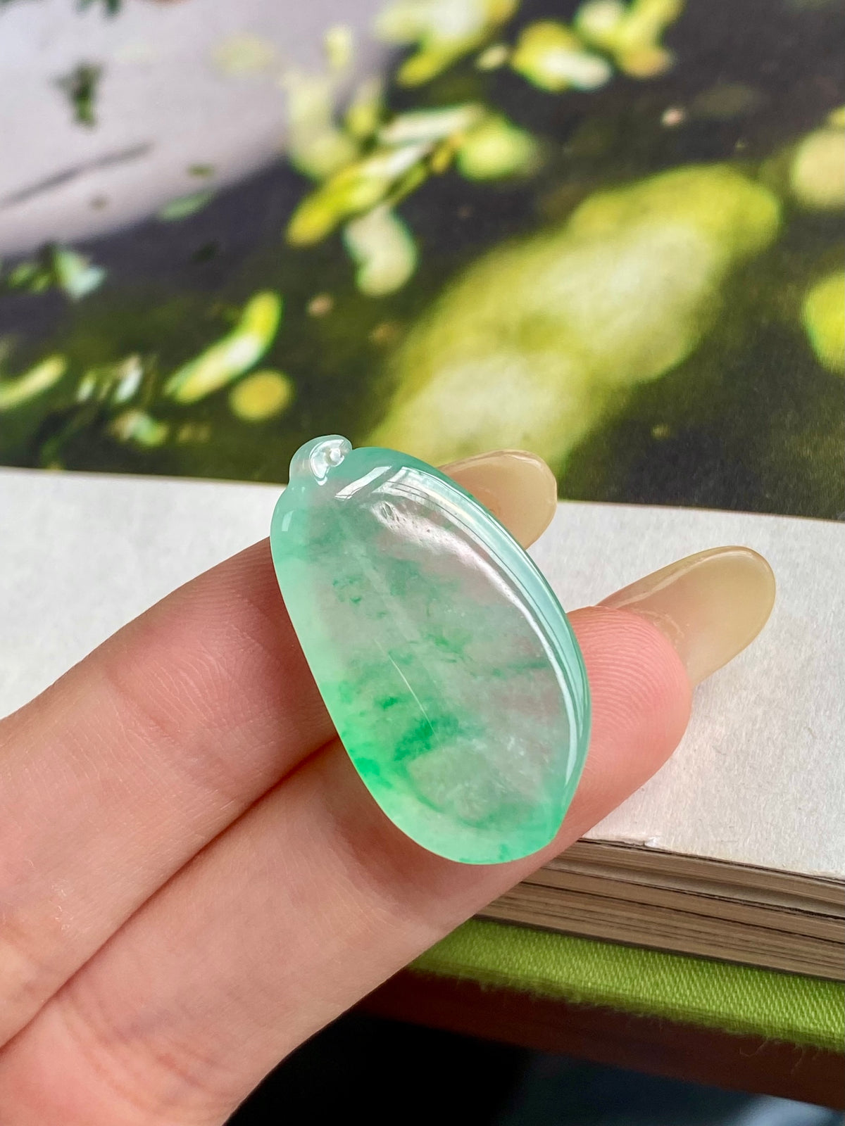 Light green jadeite melon pendant close-up, translucent teardrop with top loop bail