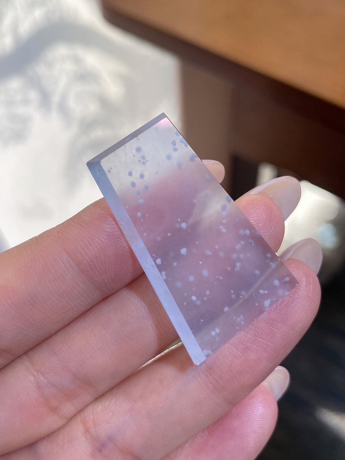 Jadeite rough stone tablet with frosty speckled inclusions, held in hand