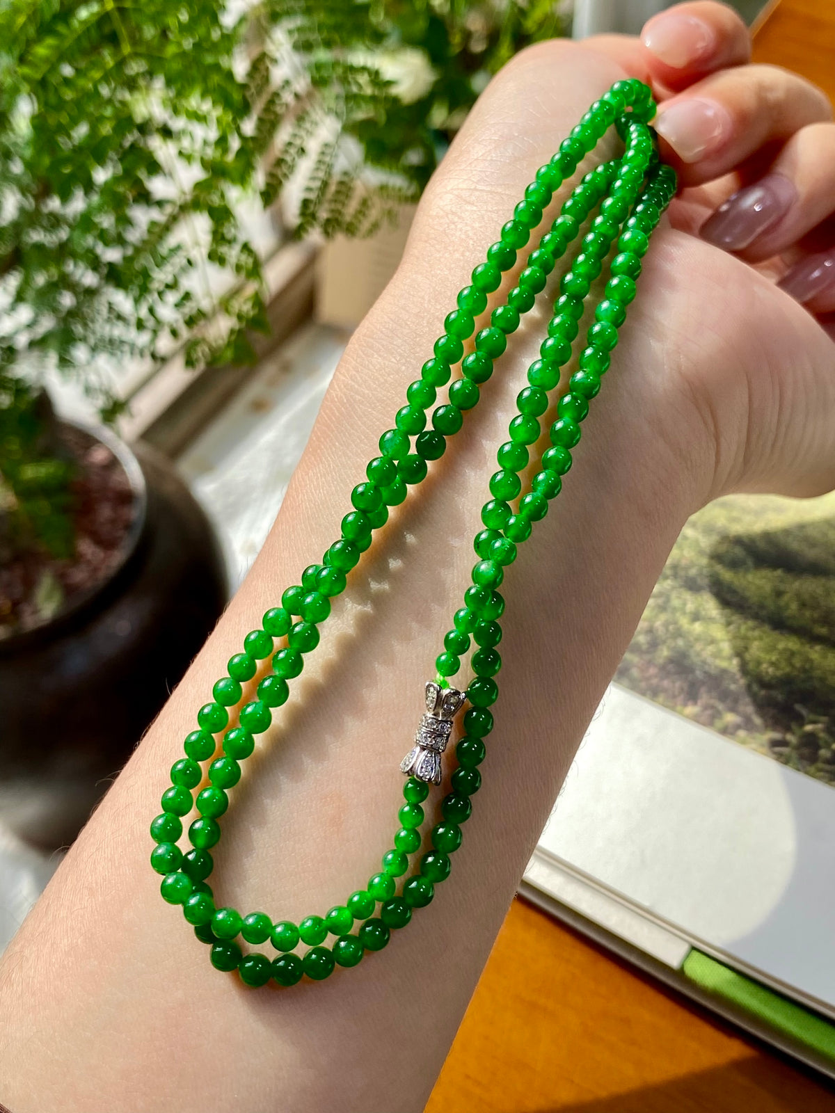 Green jadeite bead necklace with layered loops and silver clasp at the end strand