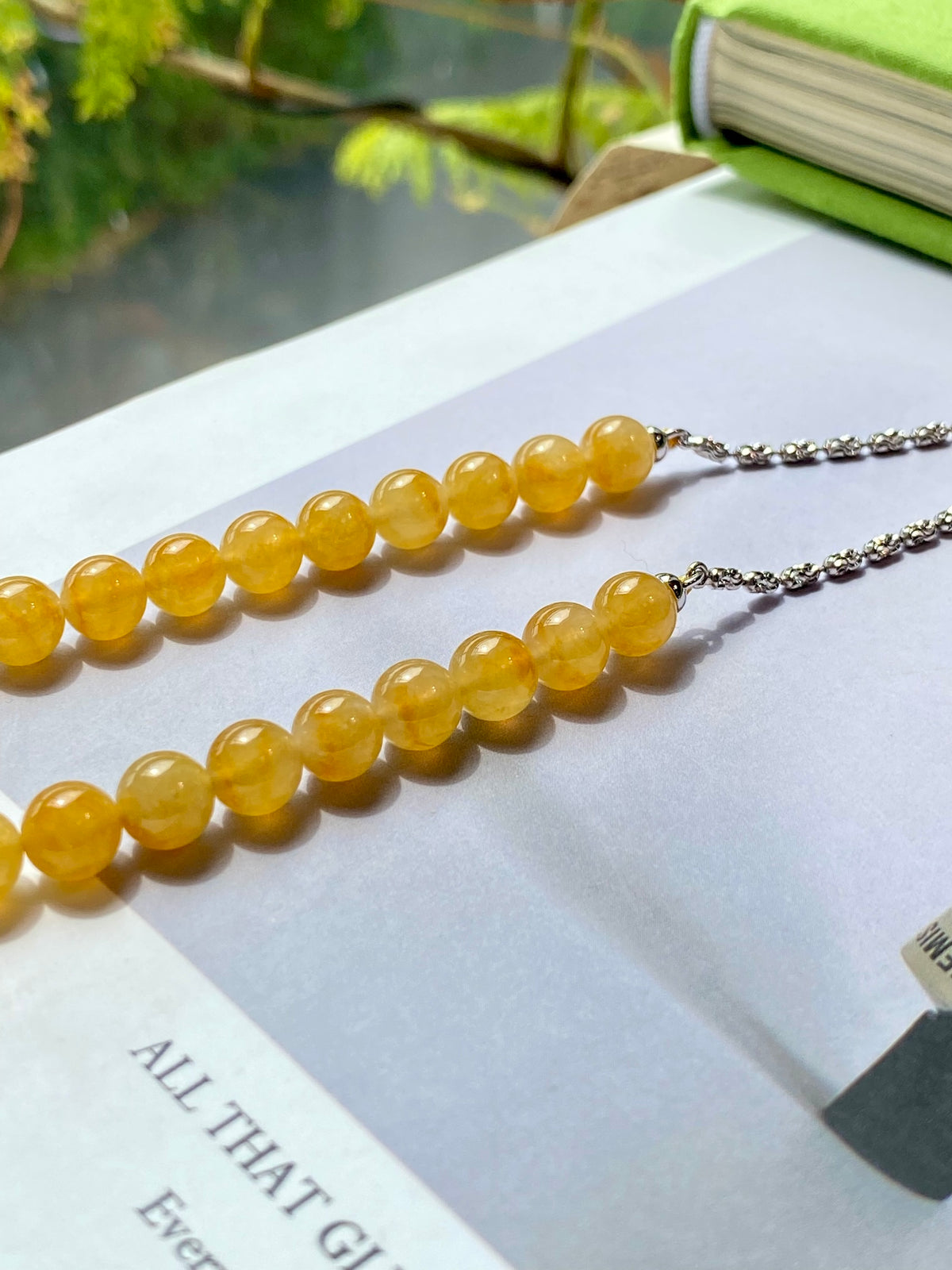 Golden-yellow round bead necklace strand with silver-toned chain ends on display