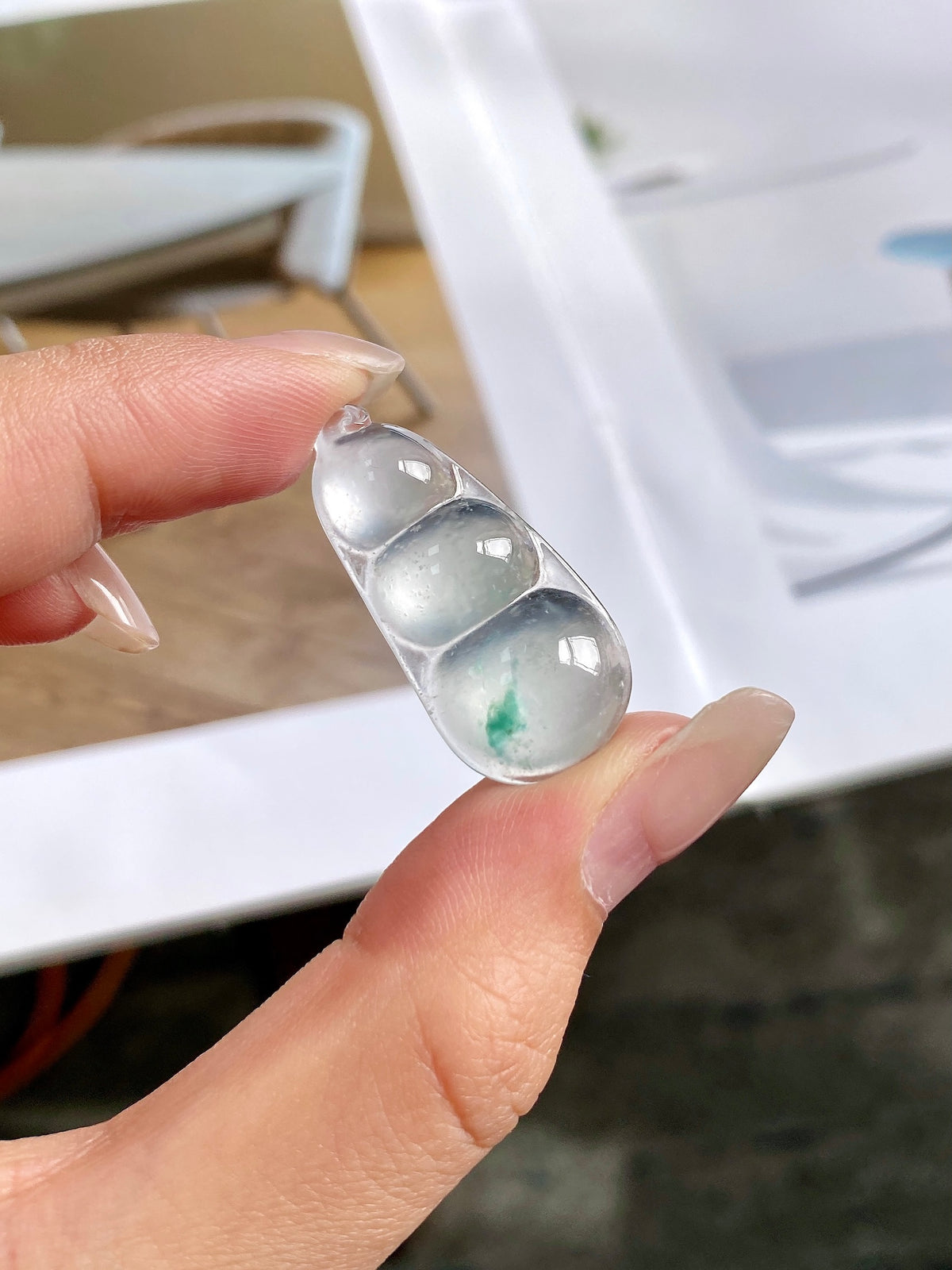 Green-flecked jadeite bean pendant in silver bezel, close-up on stone