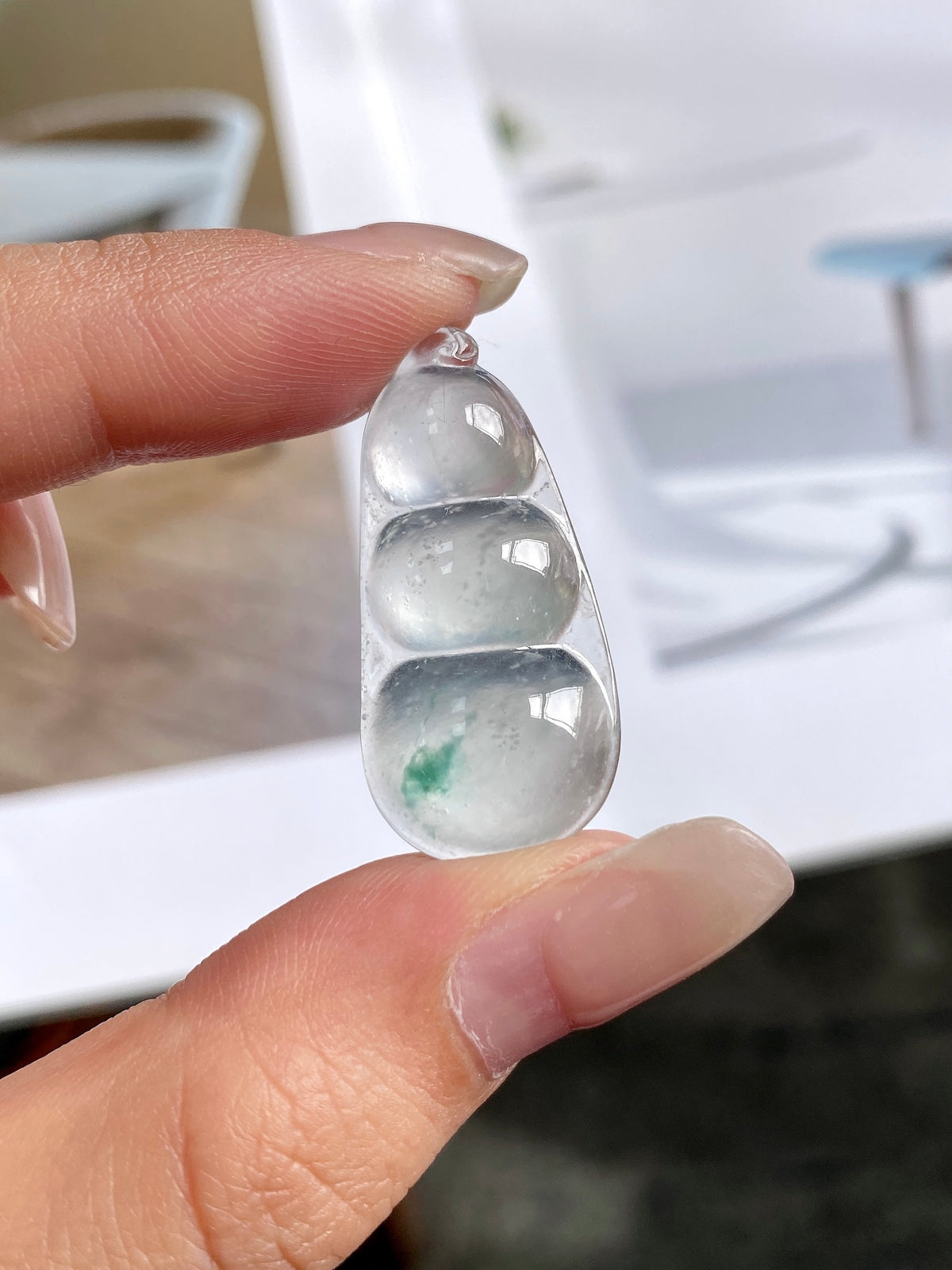 Green-flecked jadeite bean pendant in silver bezel, side view close-up