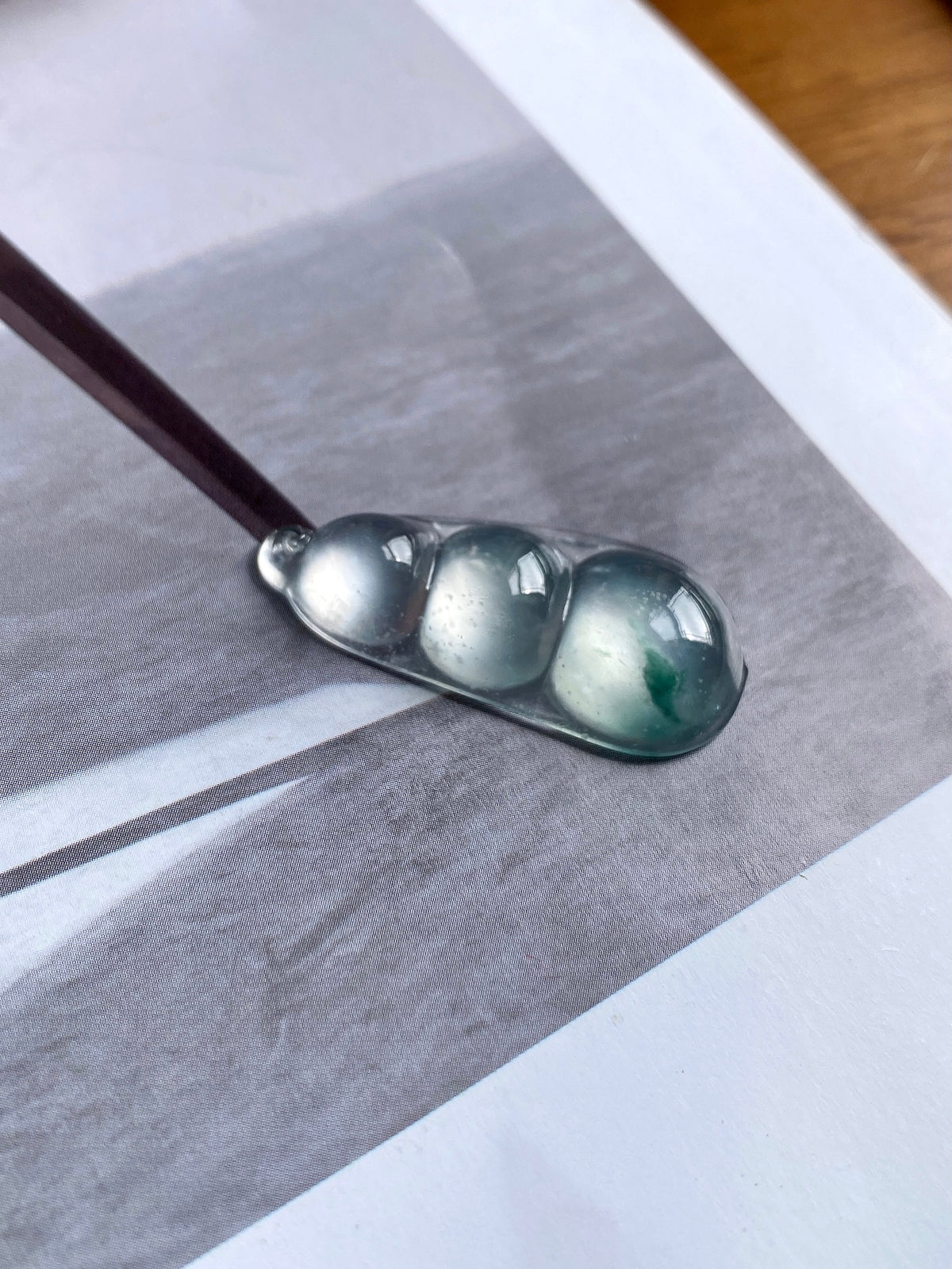 Green-flecked jadeite bean pendant in silver bezel, angled close-up