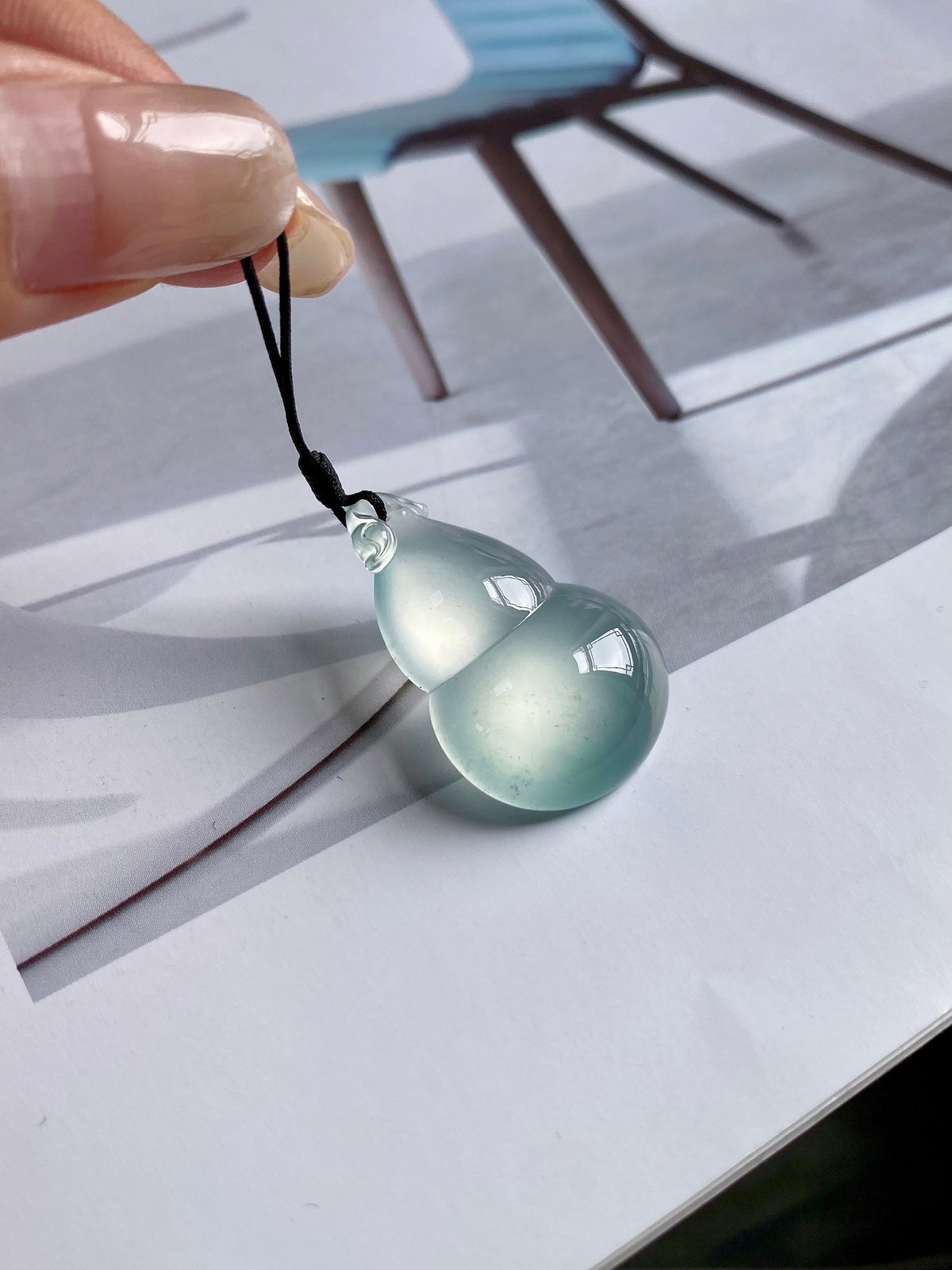 Jadeite gourd pendant with light green teardrop stone and black cord loop