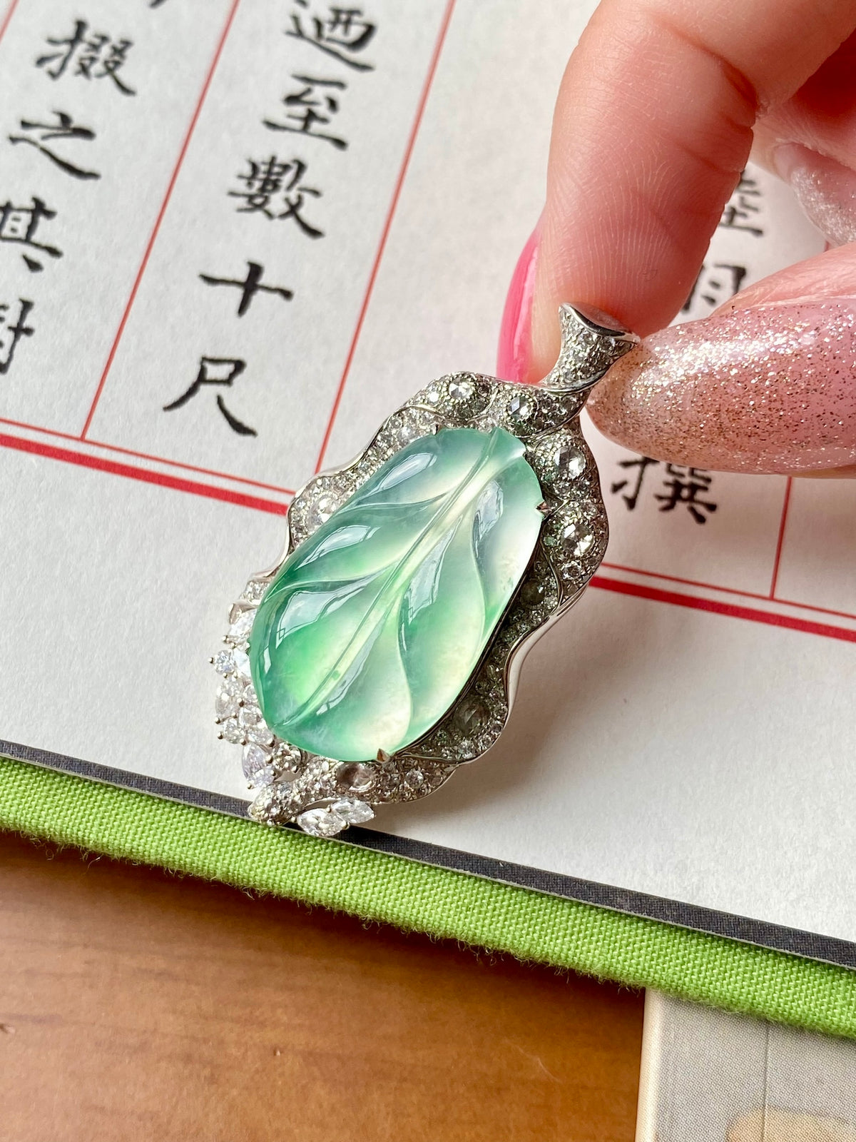 Green oval leaf pendant with silver-tone prong setting and clear stone border