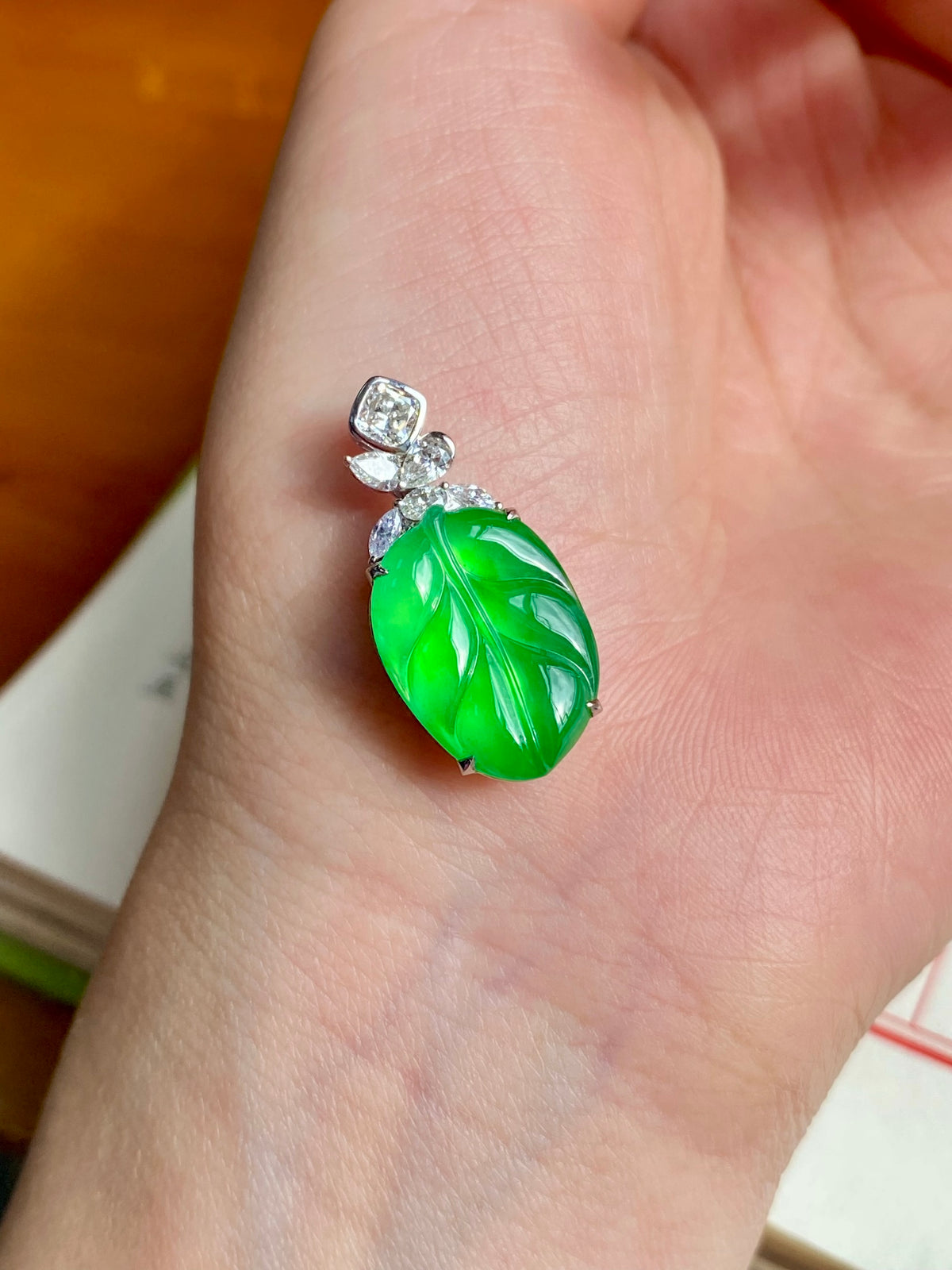Green carved jade leaf pendant with prong-set clear stones on a silver mount