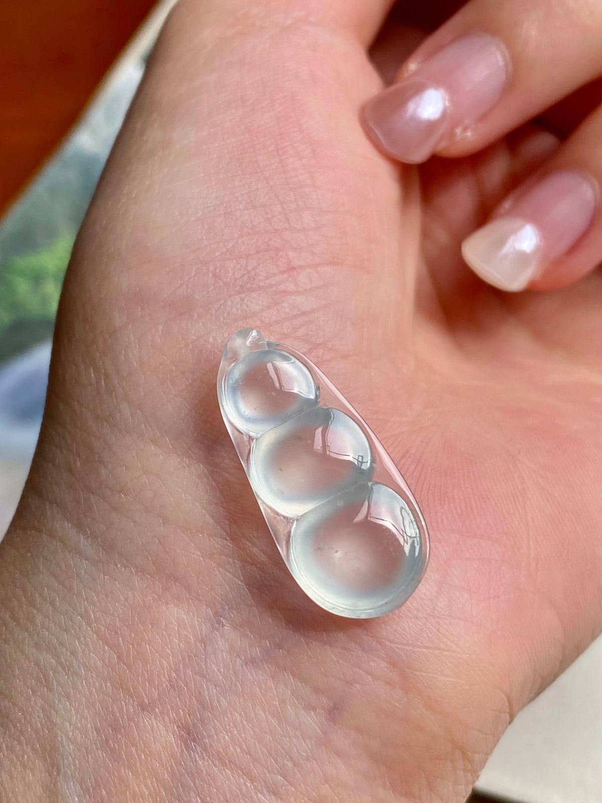 Jadeite bean pendant on hand, three translucent milky white oval beans in silver