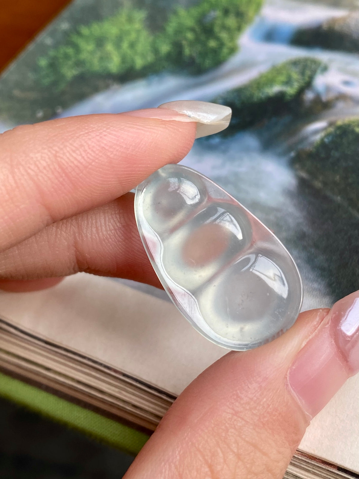 Jadeite bean pendant close-up; translucent milky white oval stone, unset setting