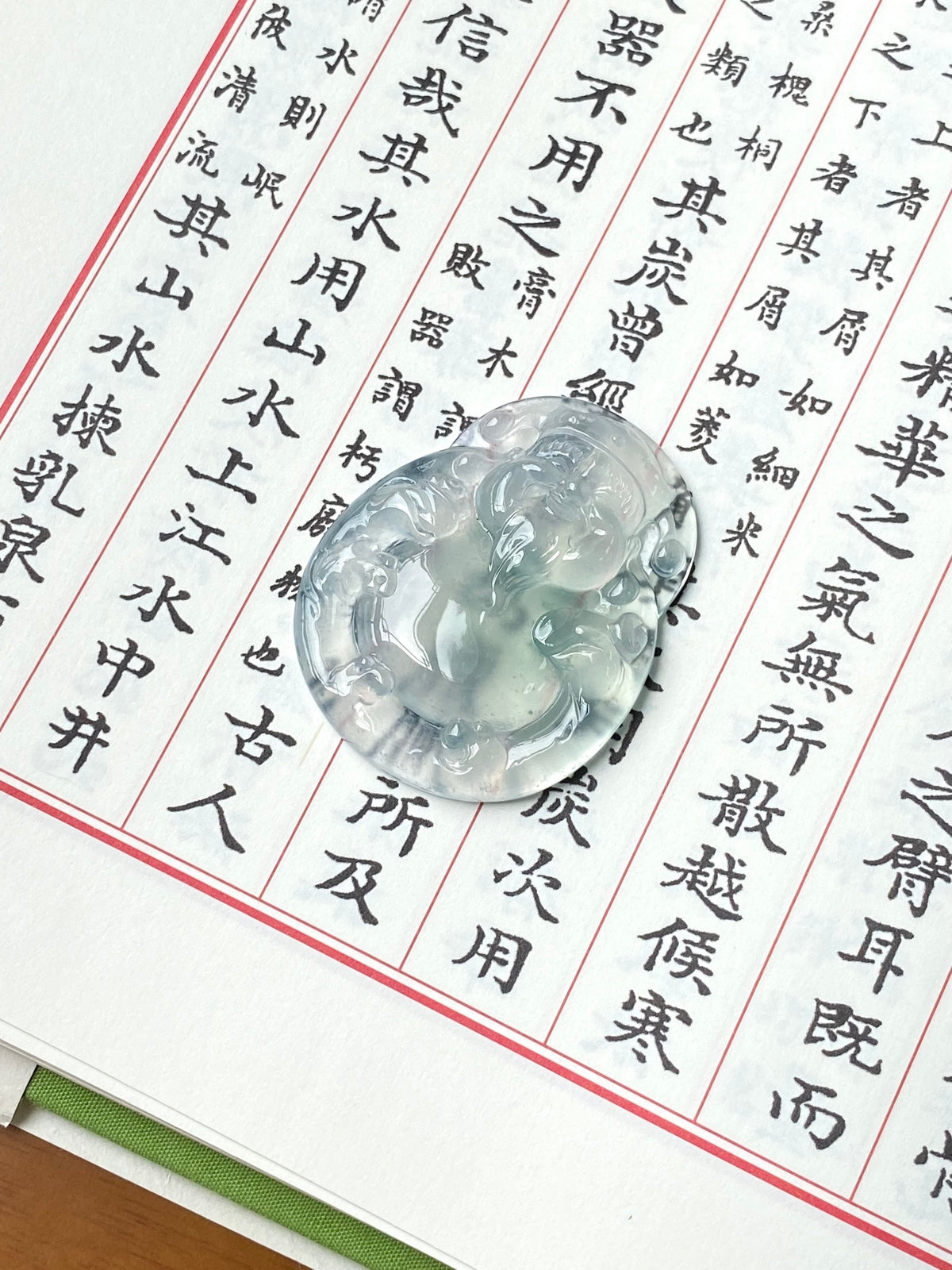 Icy white jadeite money god pendant, oval carved relief in pale green