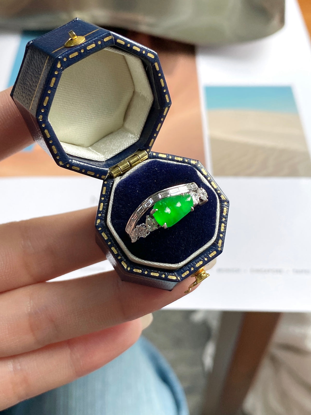Green jadeite bean ring in open box, silver band with bright green center stone