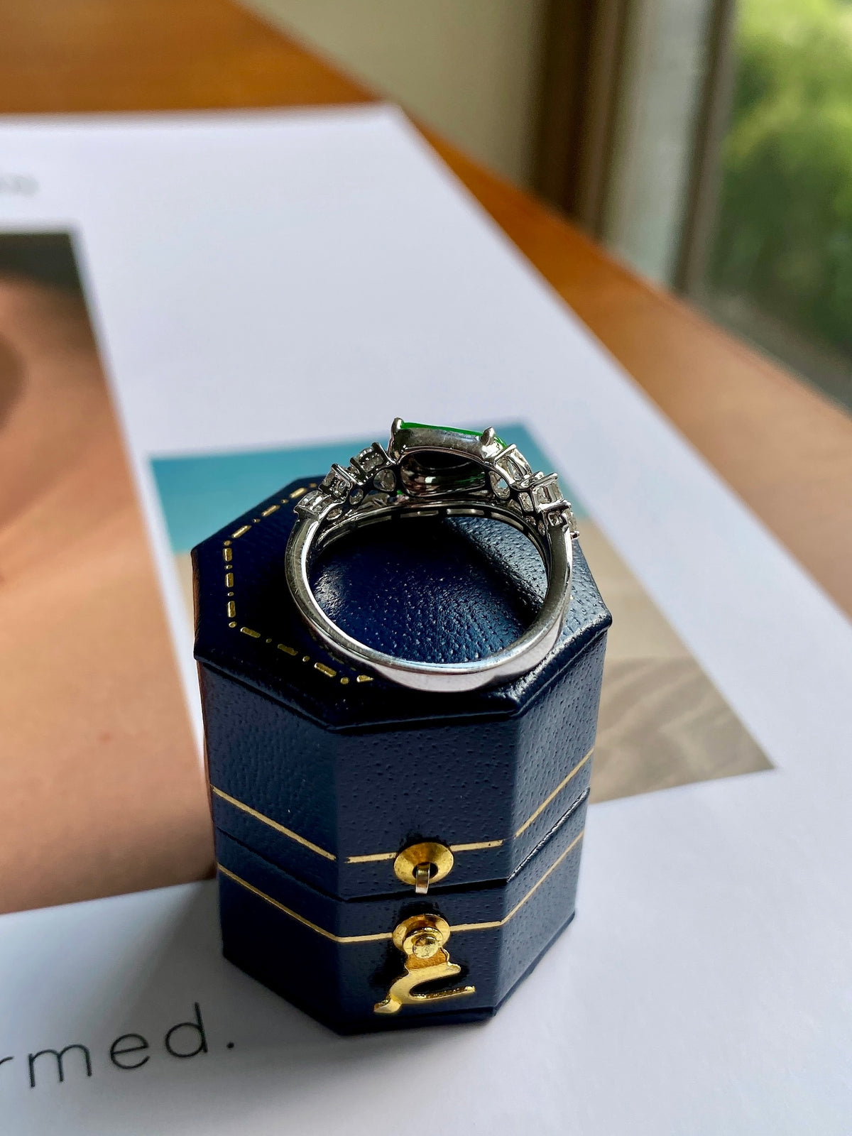Silver jadeite bean ring with green center stone, displayed in navy gift box