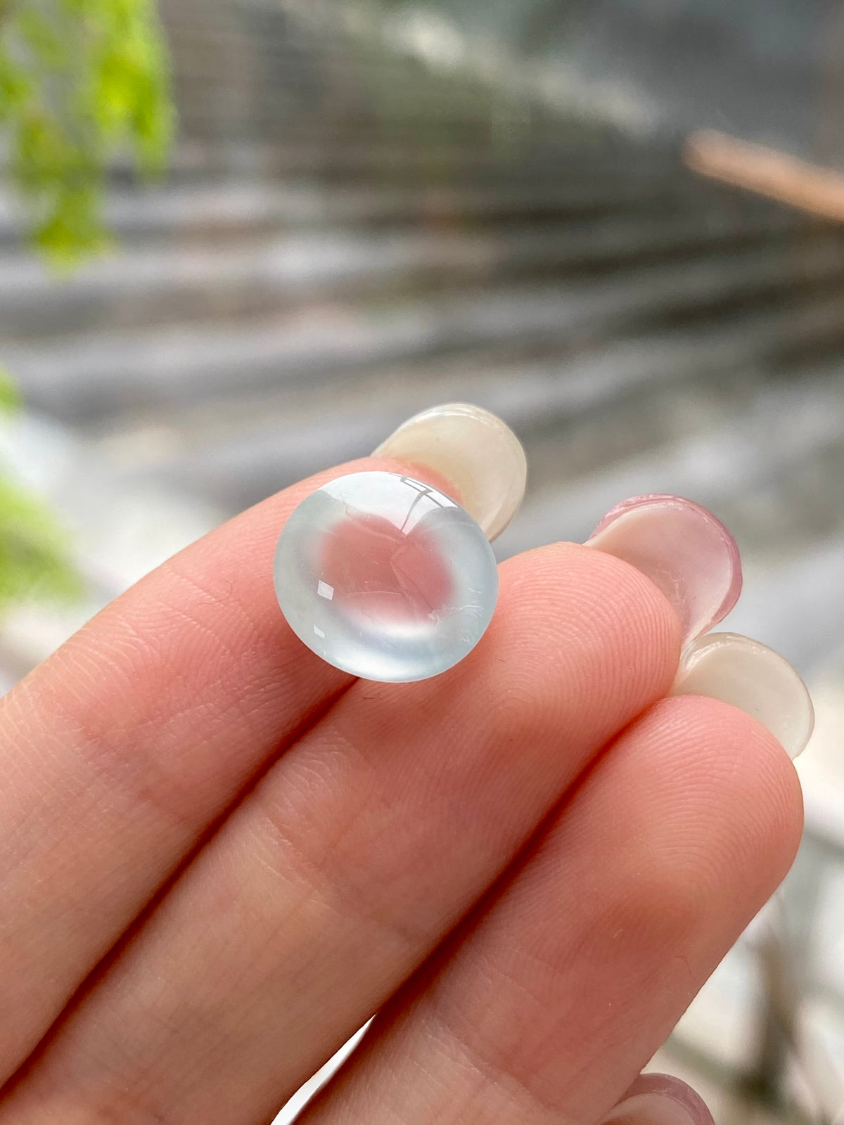 Jadeite cabochon loose stone, domed translucent white held between fingers