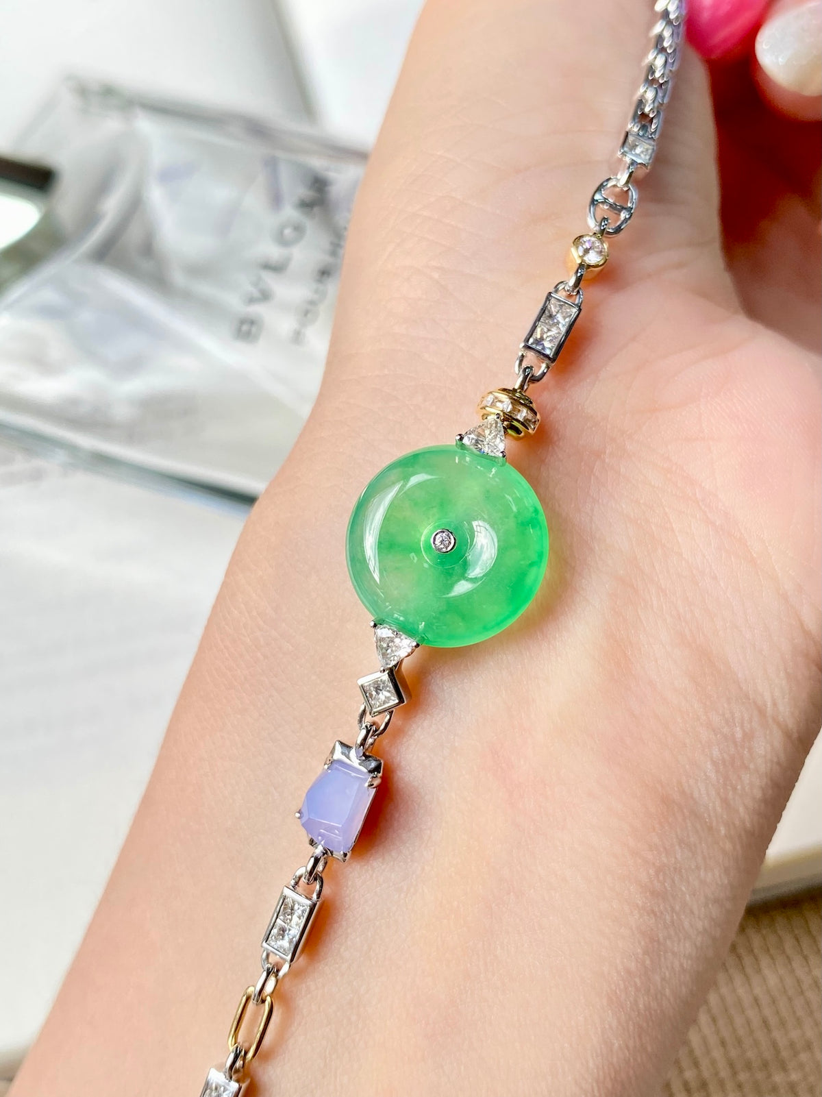 Jadeite donut bracelet on wrist with green round charm and purple accent stone
