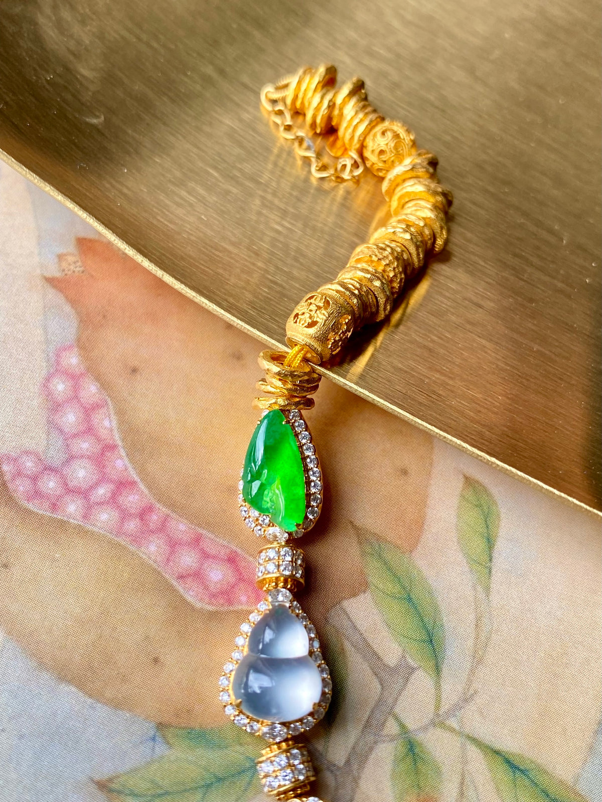 Gold jadeite gourd bracelet with green teardrop stones and blue round centerpiece