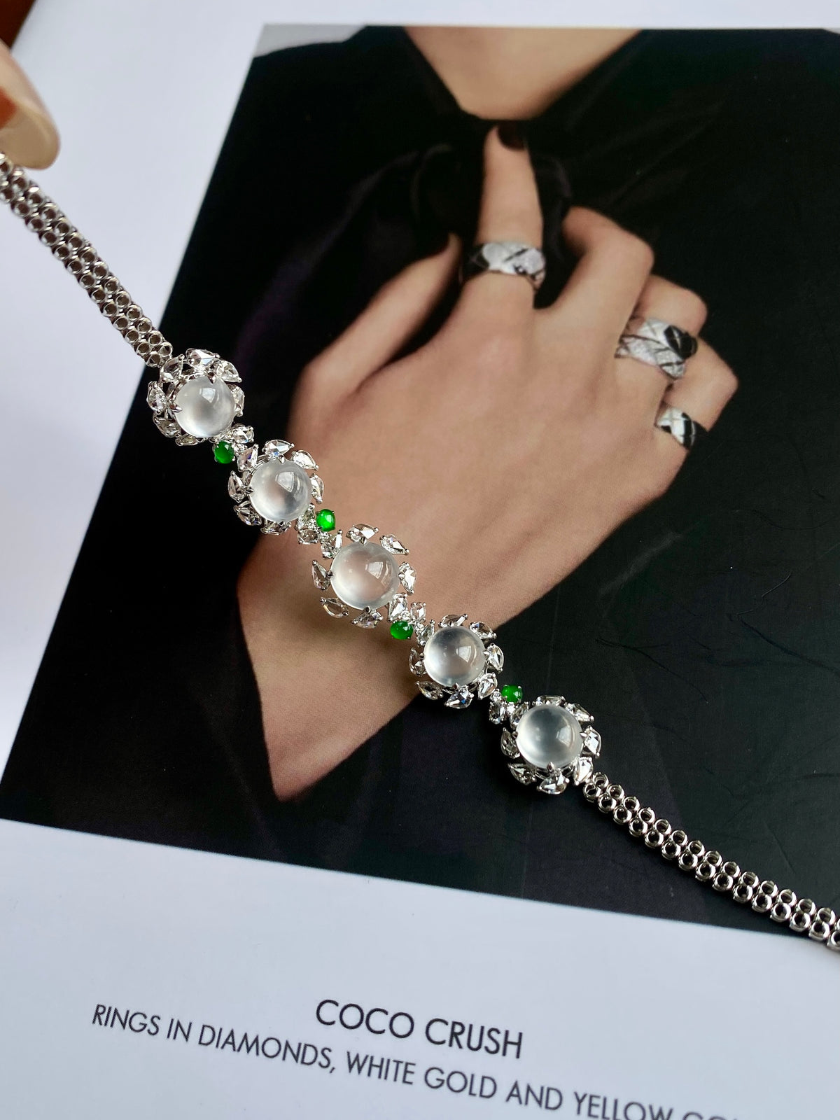 Silver-tone cabochon bracelet on hand, featuring oval white stones and green drops