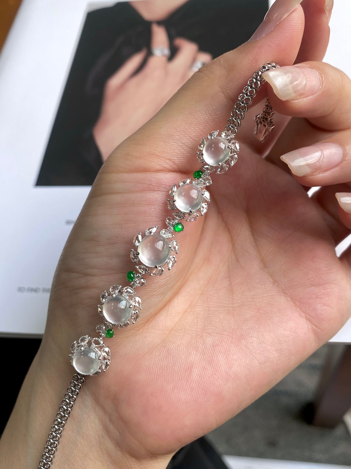 Jadeite cabochon bracelet close-up on palm, oval white stones with tiny green beads