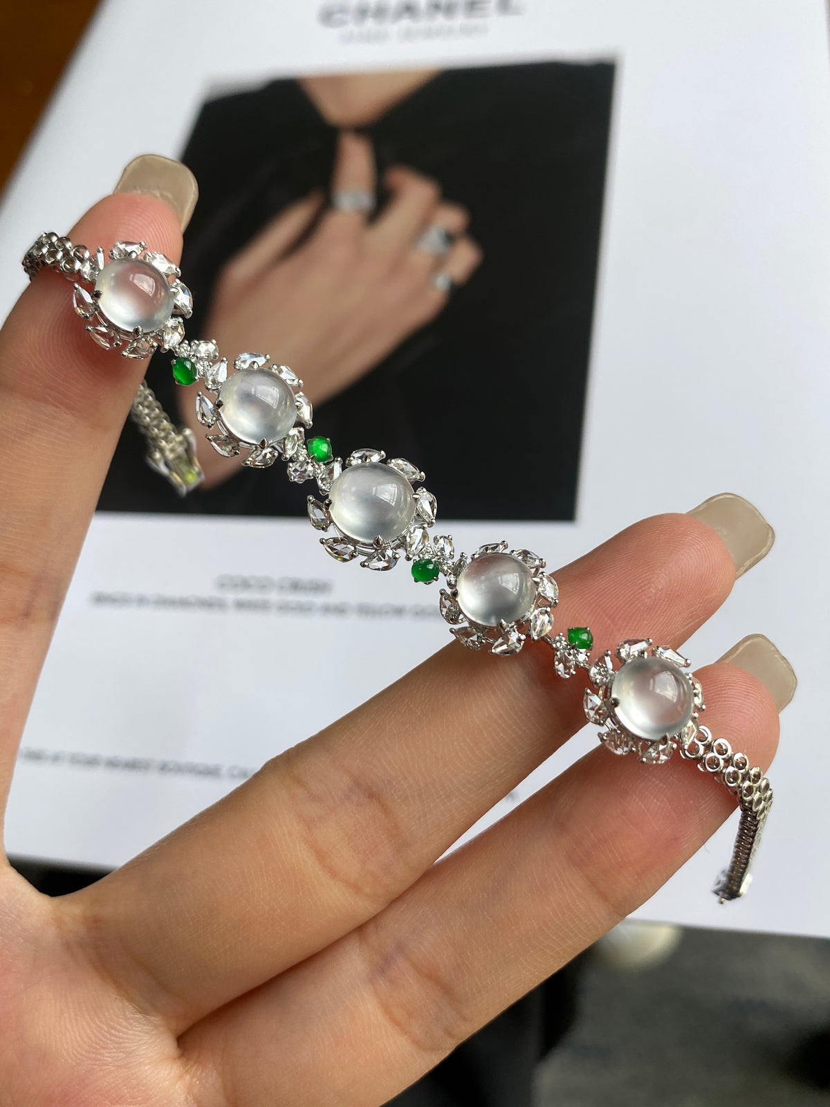 Jadeite cabochon bracelet displayed in hand, oval white stones with green spacer beads