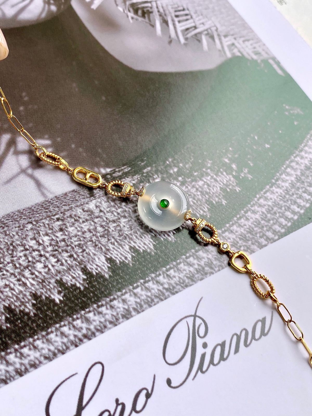 Gold safety-disc bracelet with white jade bead and green center detail