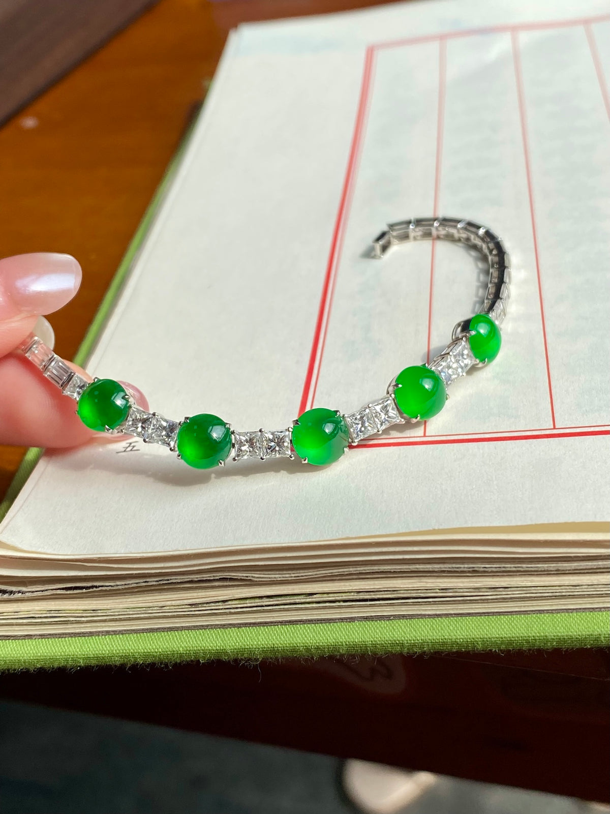Green jadeite cabochon bracelet on palm, showing clasp and round green stones