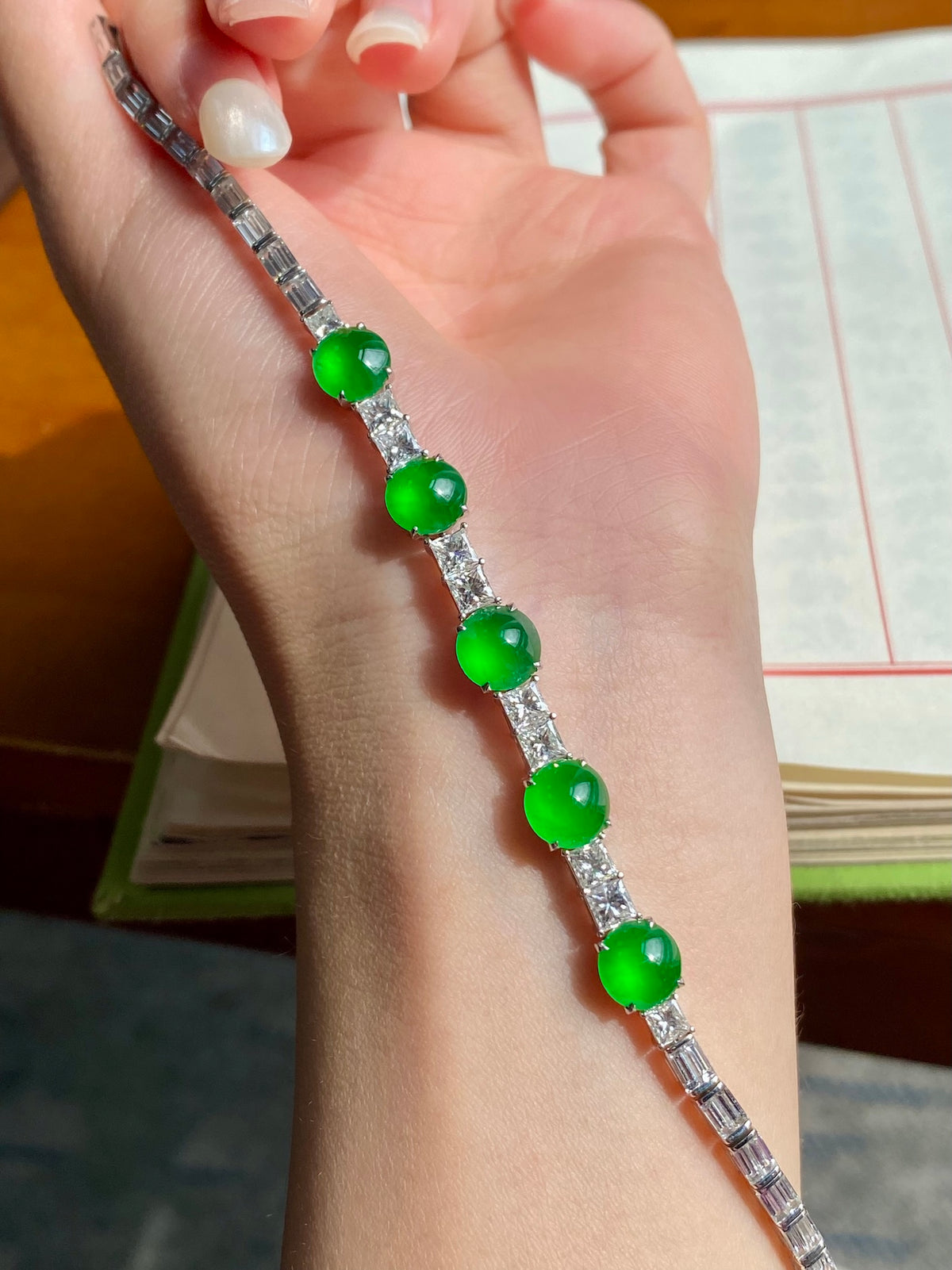 Green jadeite cabochon bracelet on hand, five round green stones with textured silver links