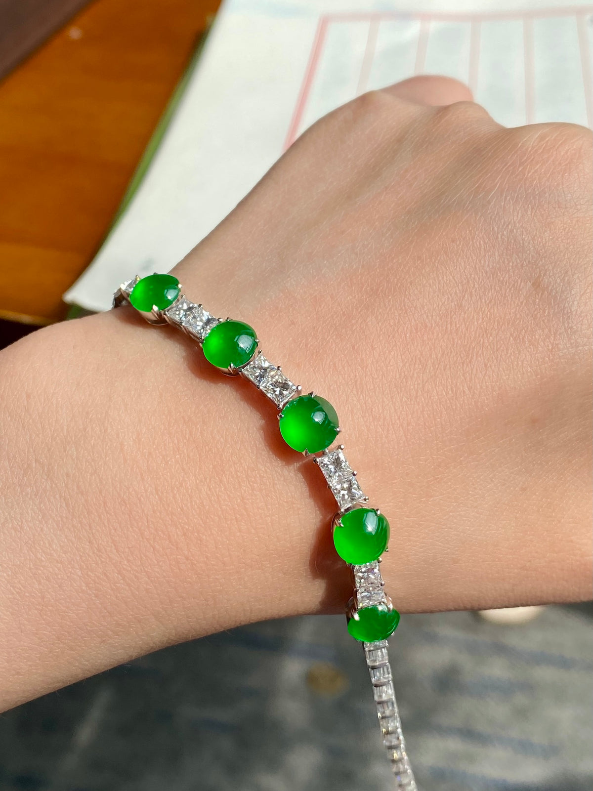 Green jadeite cabochon bracelet on wrist, round green cabochons with silver bar details