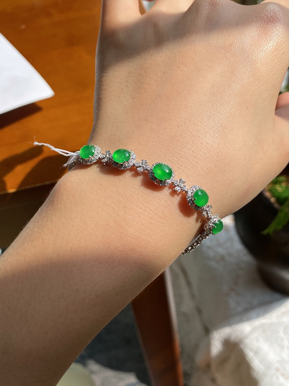 Silver bracelet with green oval jadeite cabochons and clear crystal accents on wrist