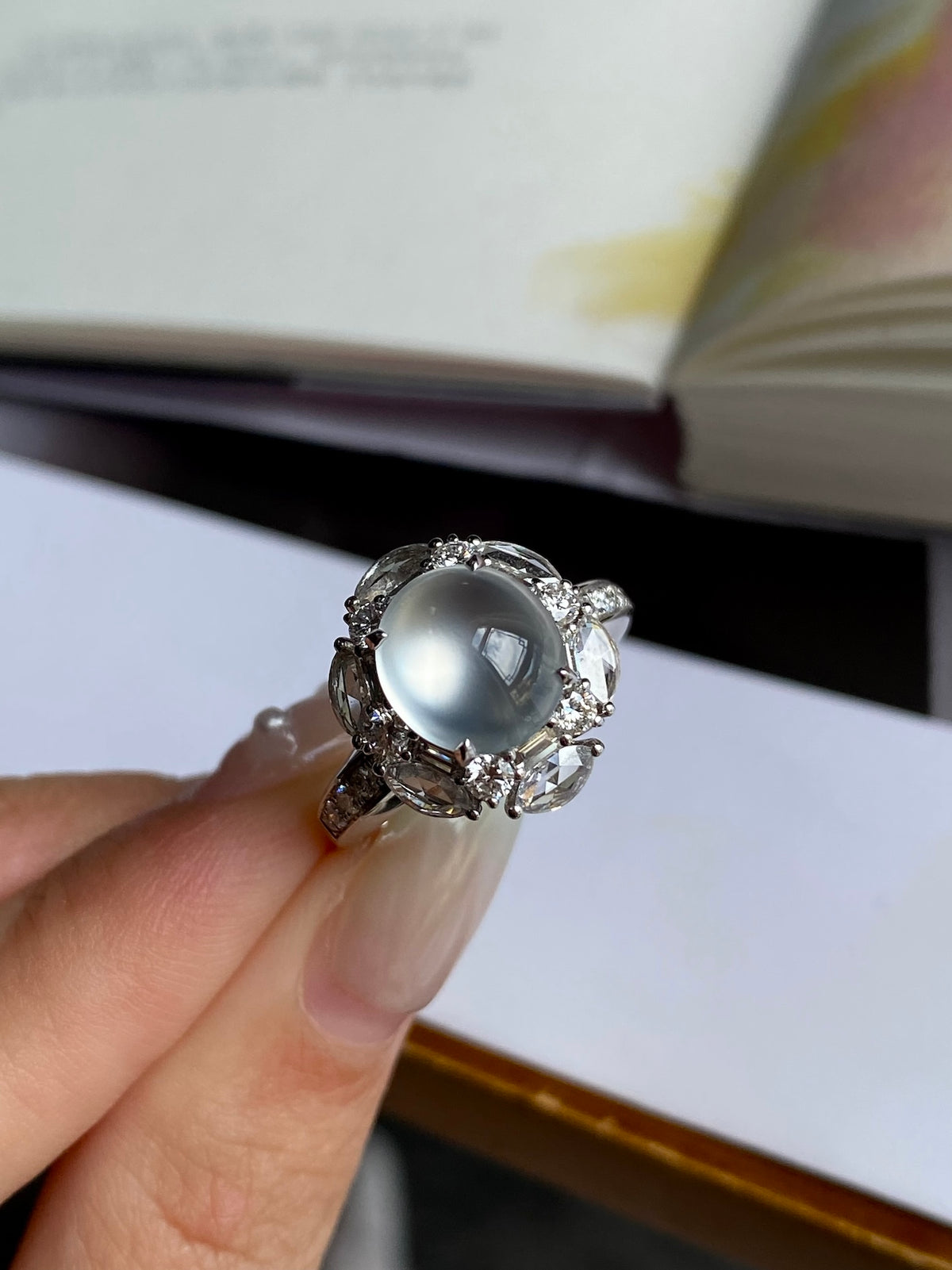 Silver-tone ring with oval cabochon and ornate halo, worn on finger