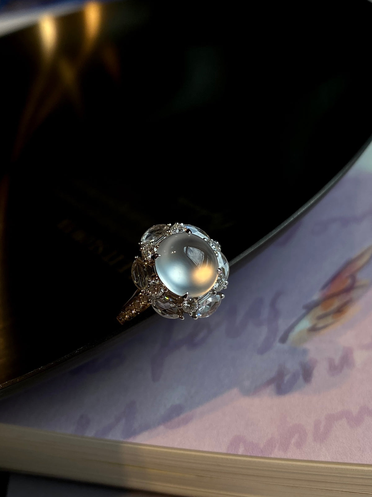 Silver-tone oval cabochon ring with sparkling halo, tilted view
