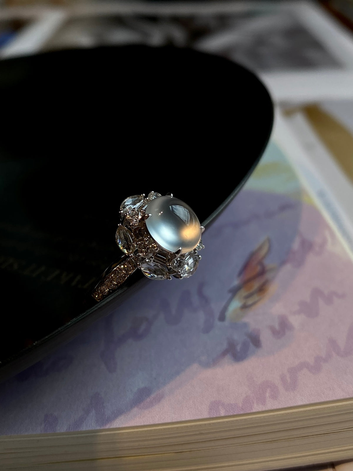 Silver-tone oval cabochon ring with sparkling halo, angled view