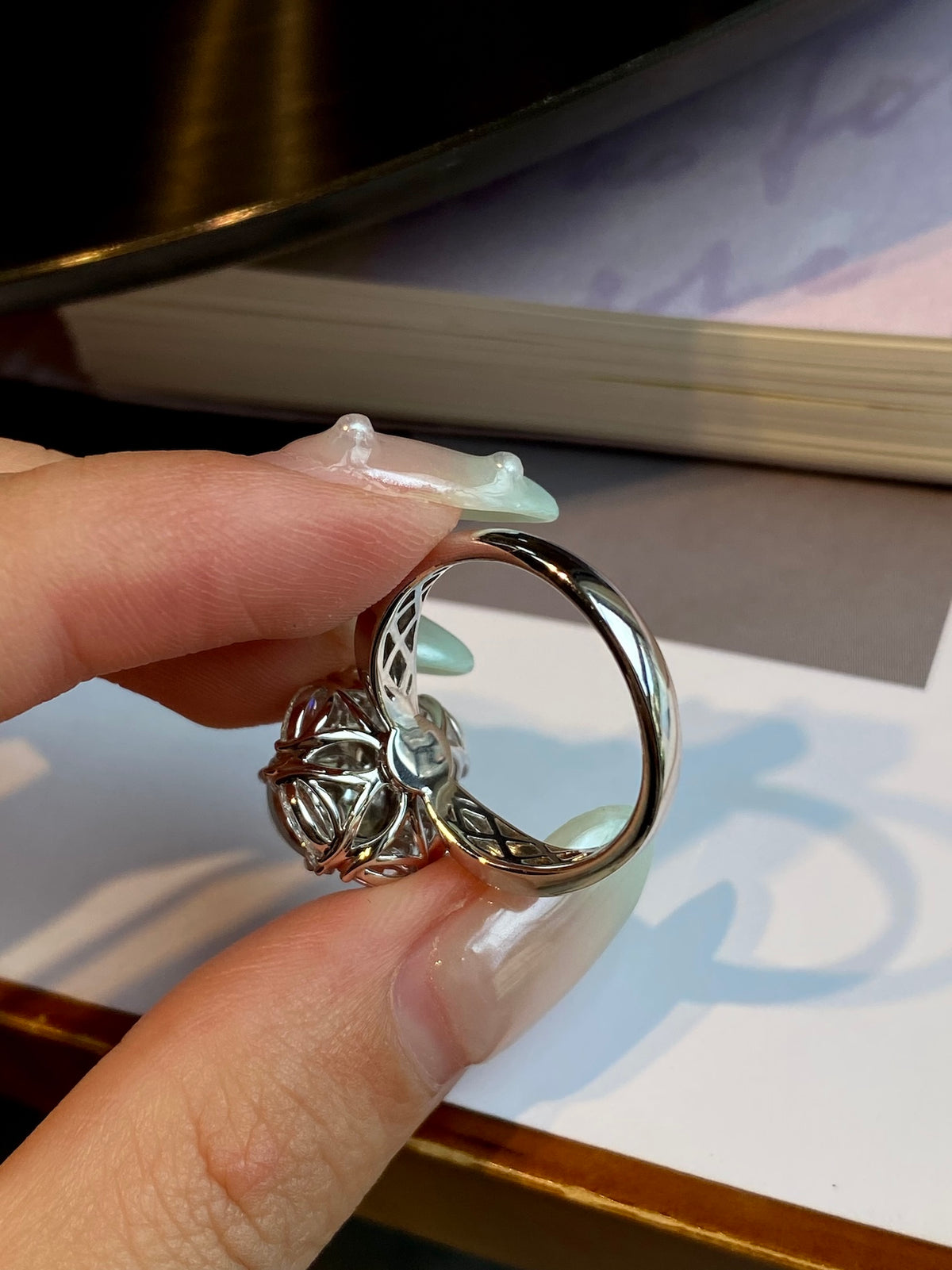 Silver-tone ring with oval cabochon and ornate halo, side view