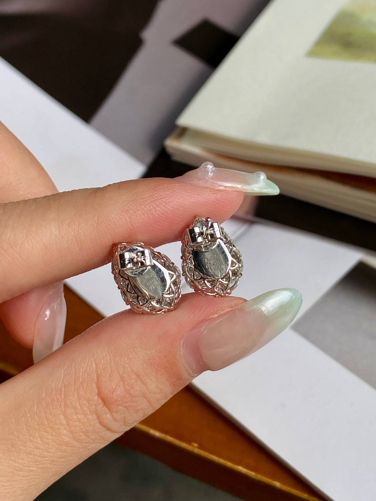 Green jadeite gourd stud earrings with crystal halo, close-up on hand