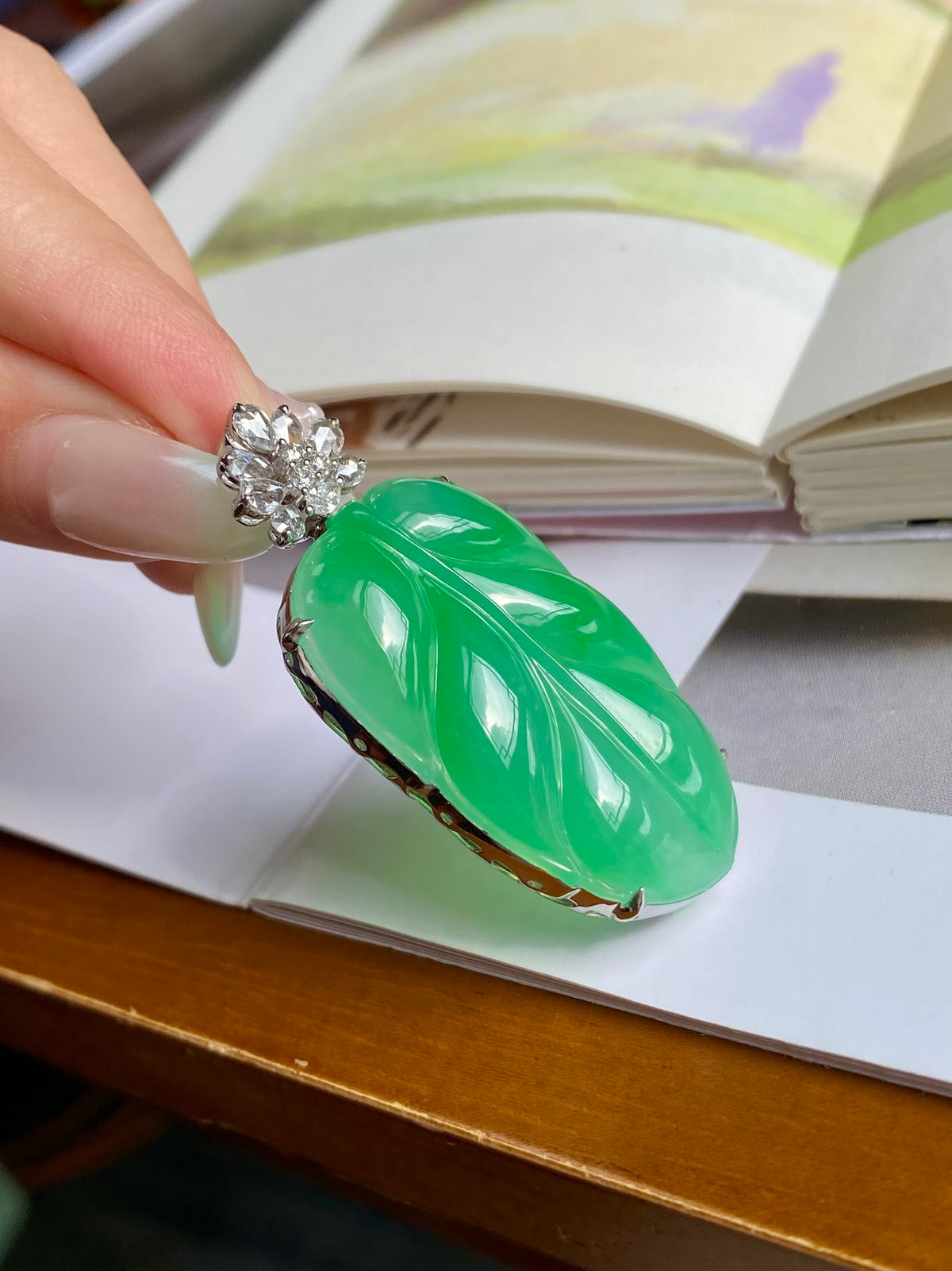 Green jadeite leaf pendant close-up, silver-tone bezel with ornate crystal top