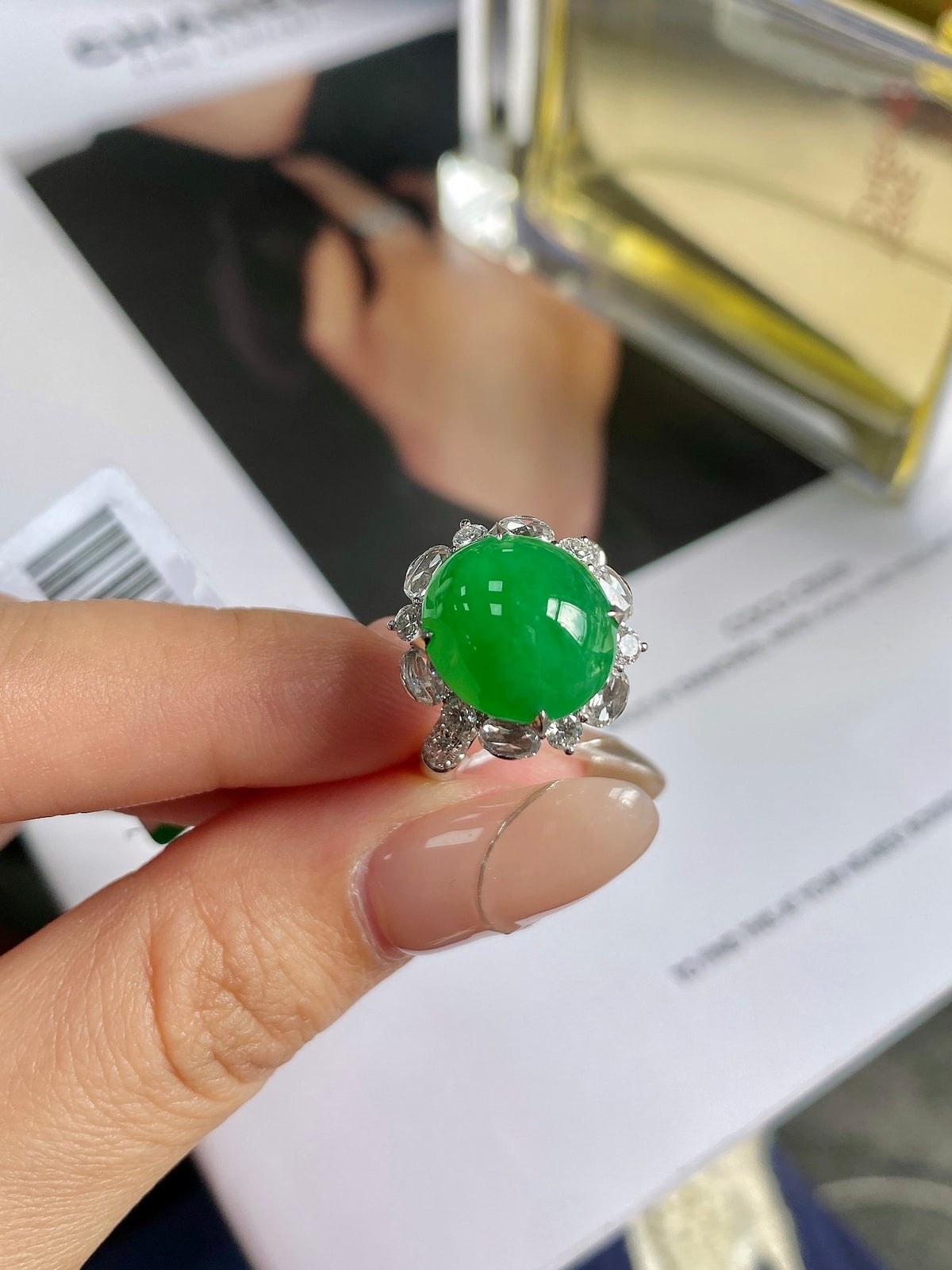 Green jadeite cabochon ring with silver prongs and diamond-like halo.