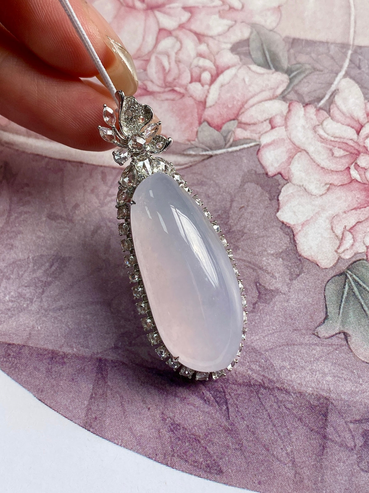 Oval lavender gemstone pendant close-up with floral bail and rhinestone edging, silver