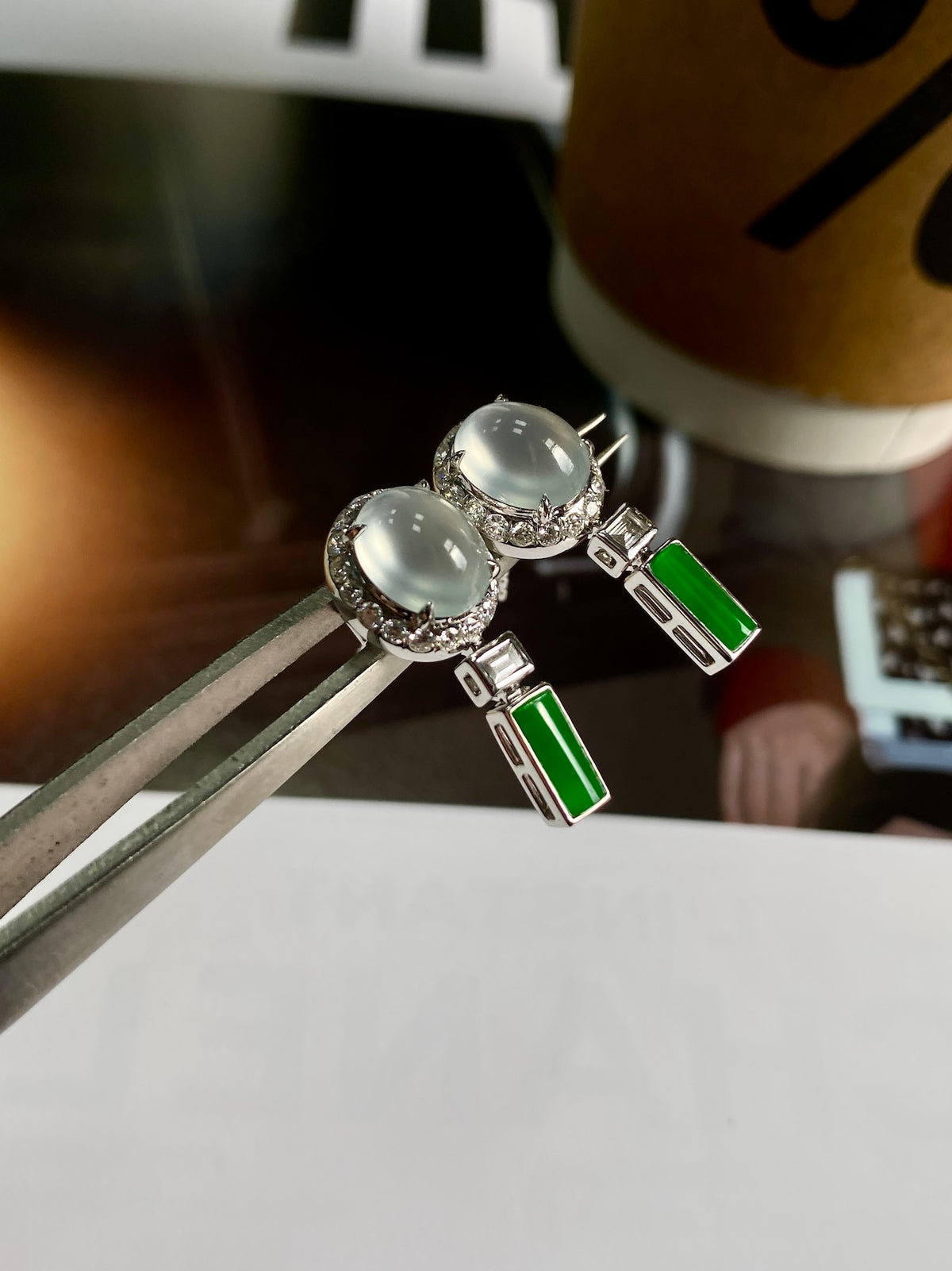 Round white cabochon stud earrings with green rectangular drops and silver prong settings