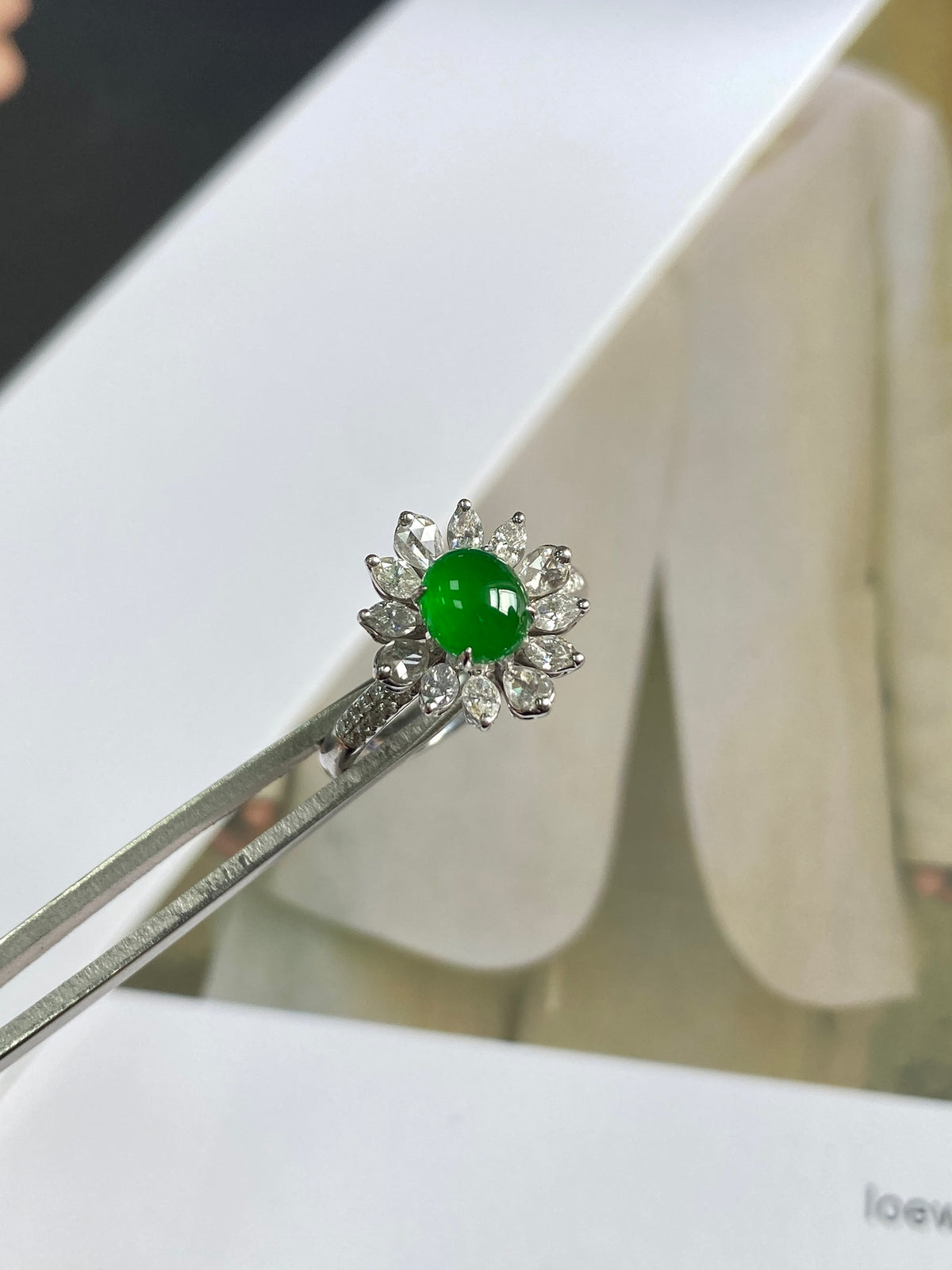 Green cabochon jadeite ring with small diamond-like cluster around the bezel