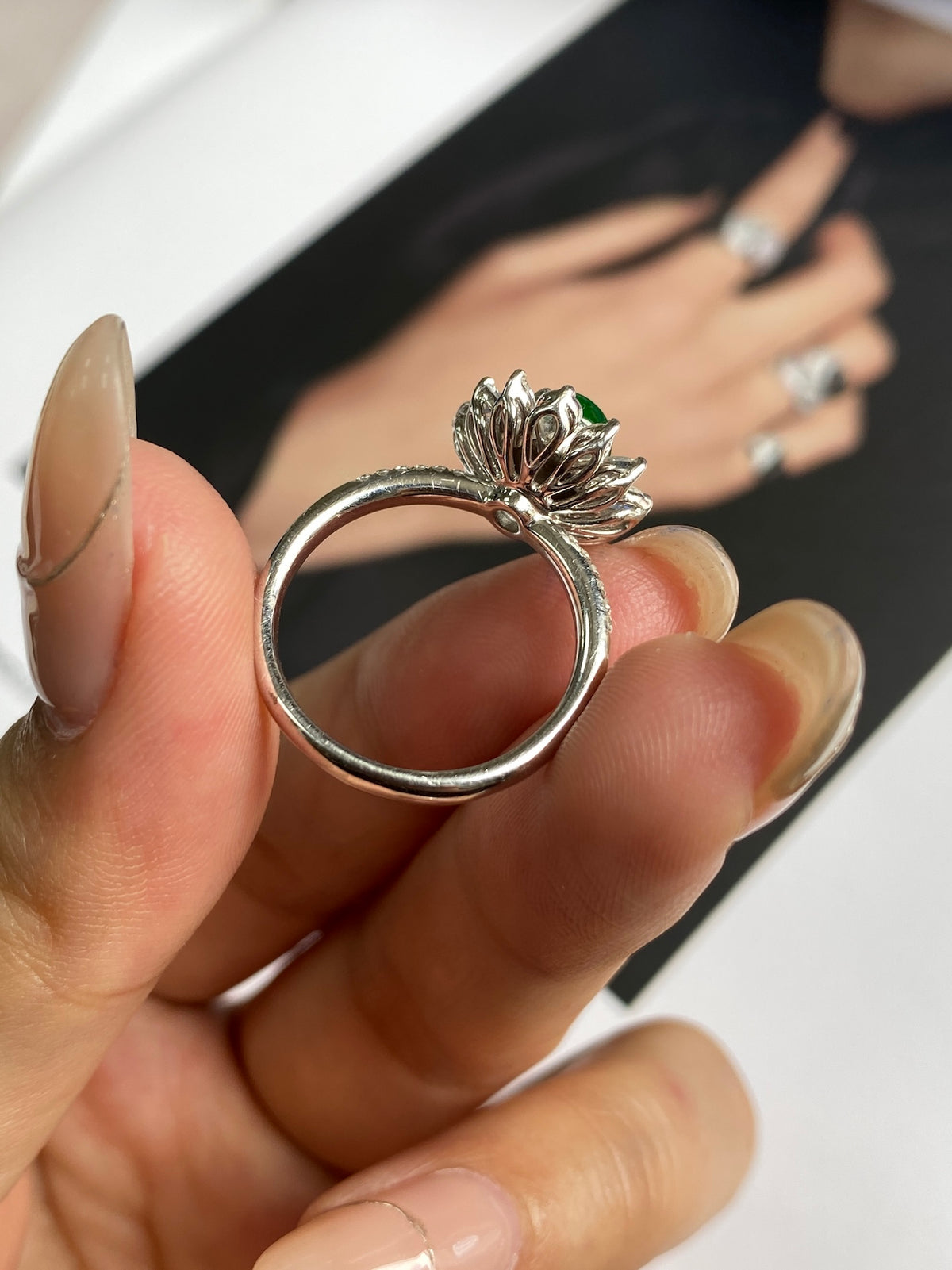 Close-up of silver jadeite cabochon ring with green center and ornate prongs