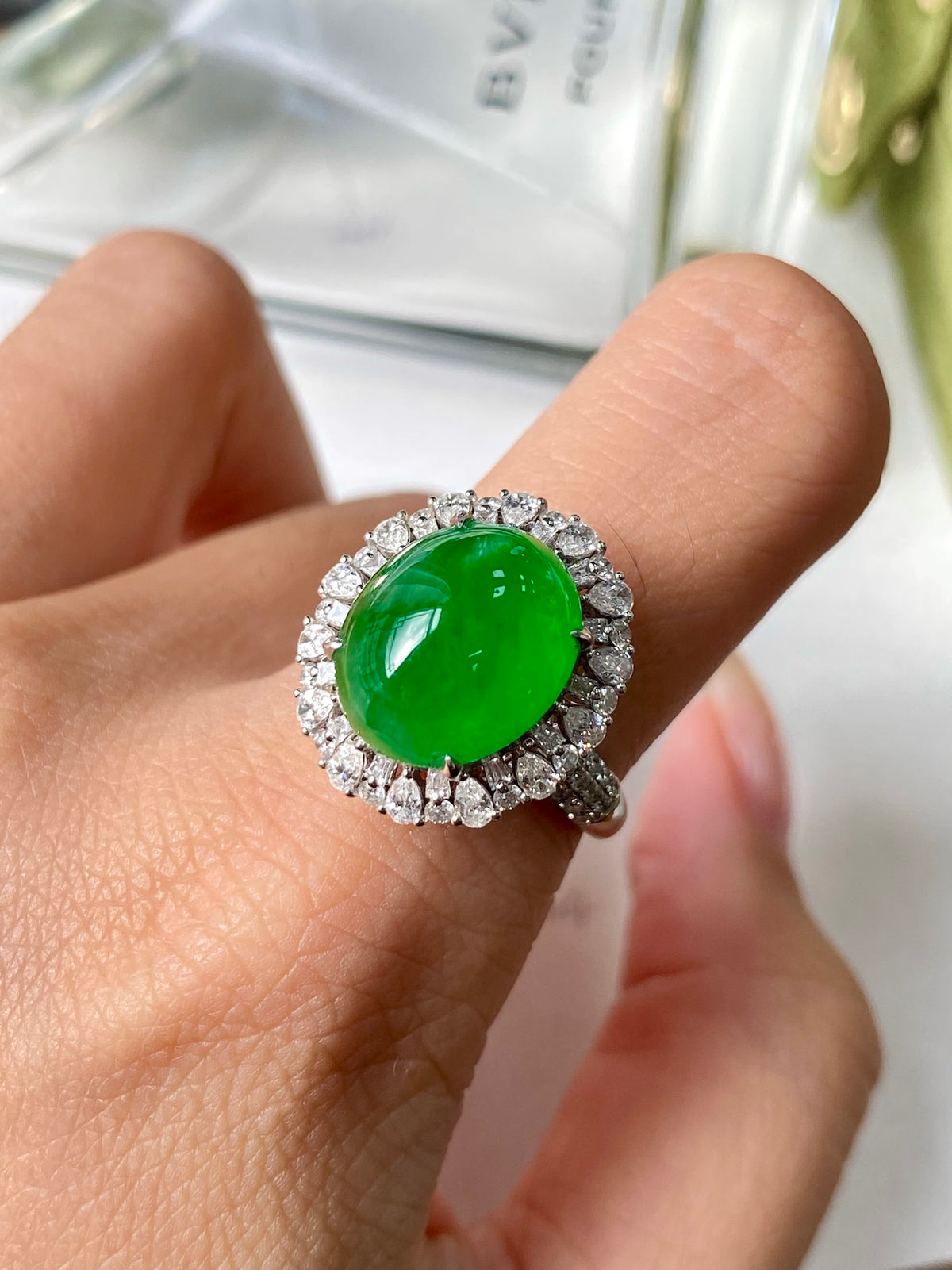 Green jadeite cabochon ring with diamond halo, worn on a finger
