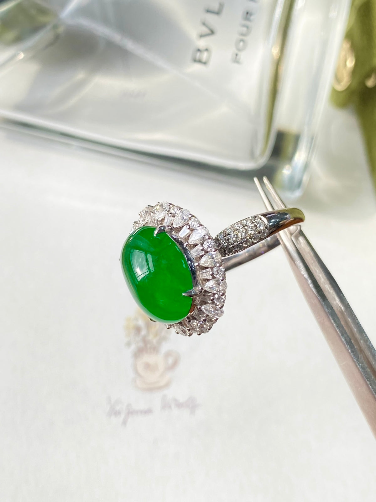 Green jadeite oval cabochon ring with sparkling diamond halo and prong setting