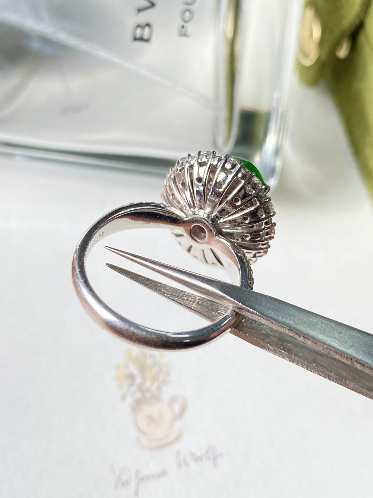 Silver ring with green jadeite cabochon and diamond halo, close-up prong view
