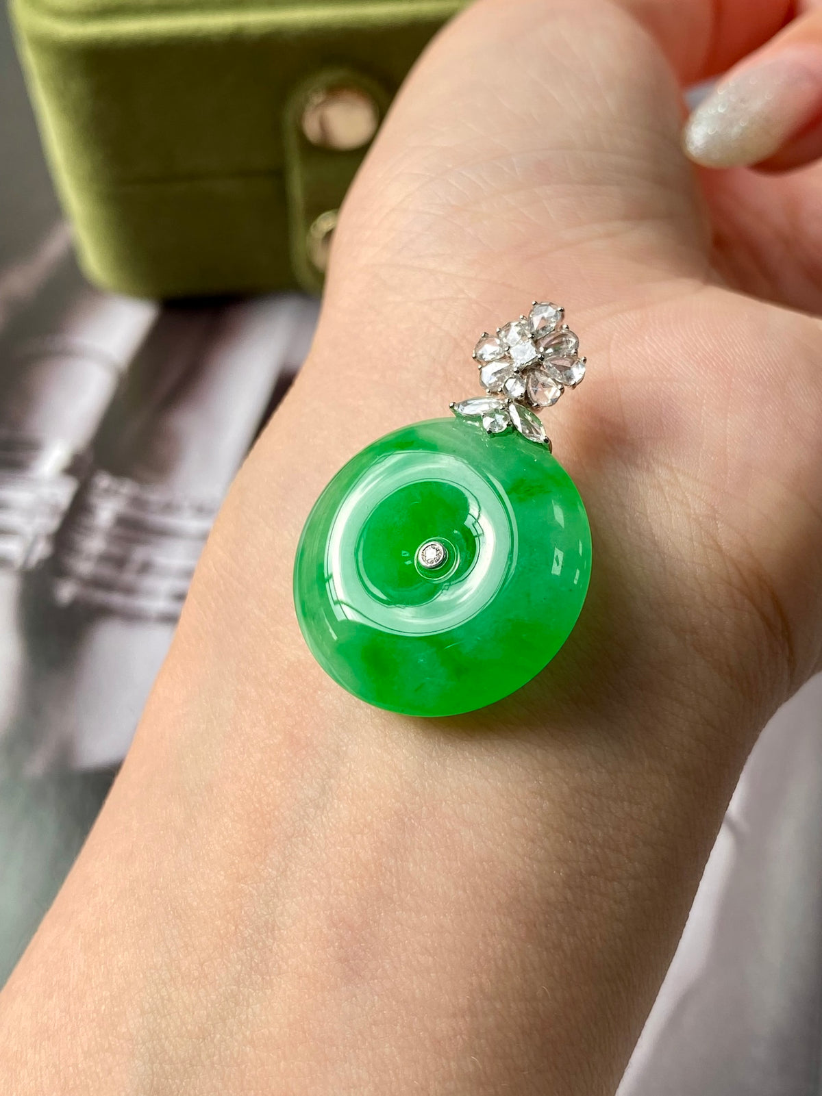 Green jadeite donut pendant with silver bail and sparkling flower-like stud cluster