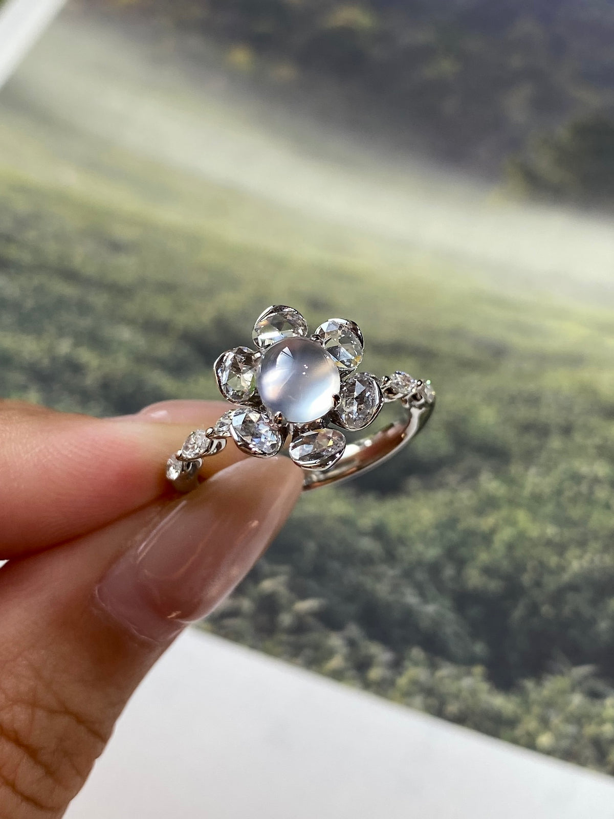 Round light gray-white cabochon ring with sparkling crystal halo and twisted band
