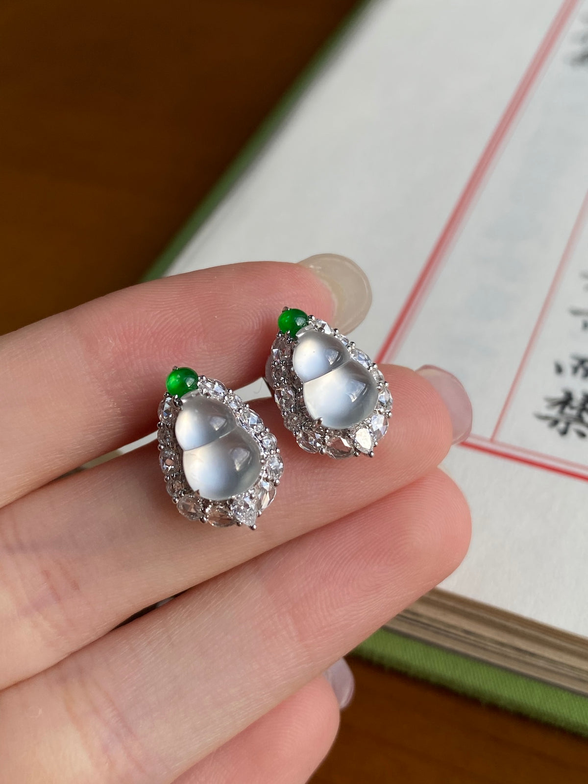 Oval stud earrings with white centers and green caps in silver-tone halo