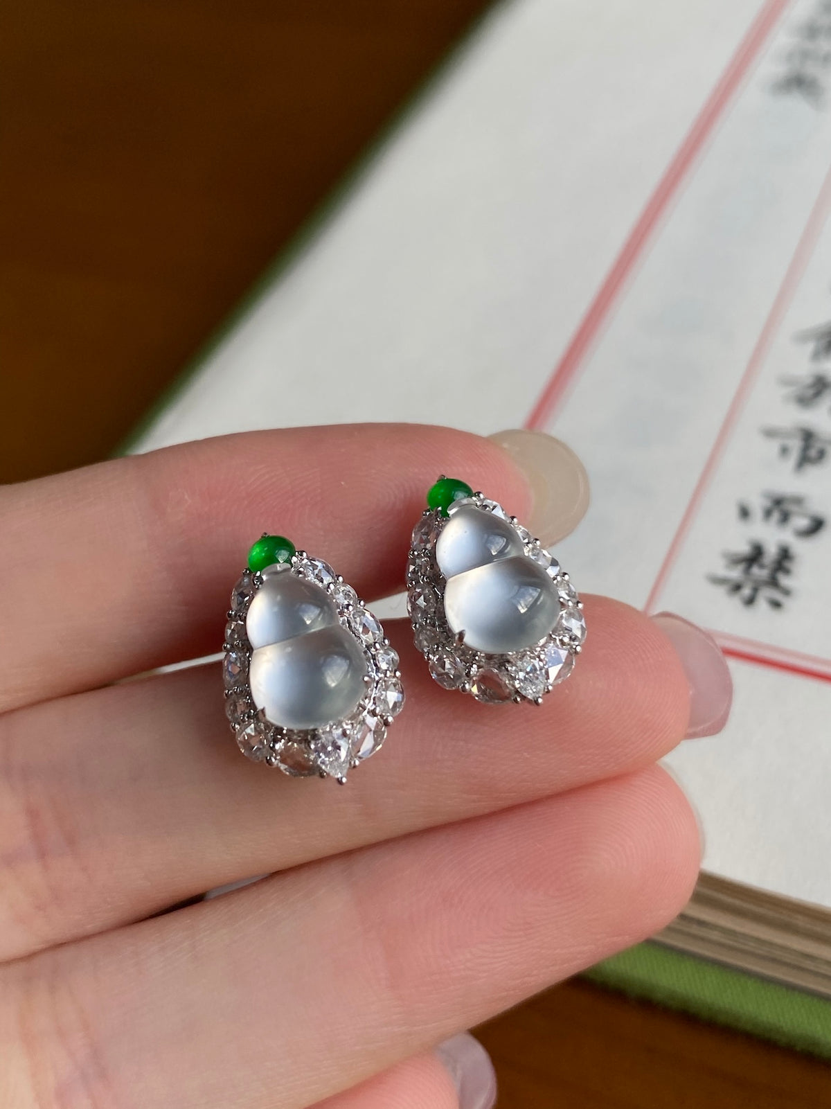 Oval stud earrings with white center, green accents, sparkling silver halo