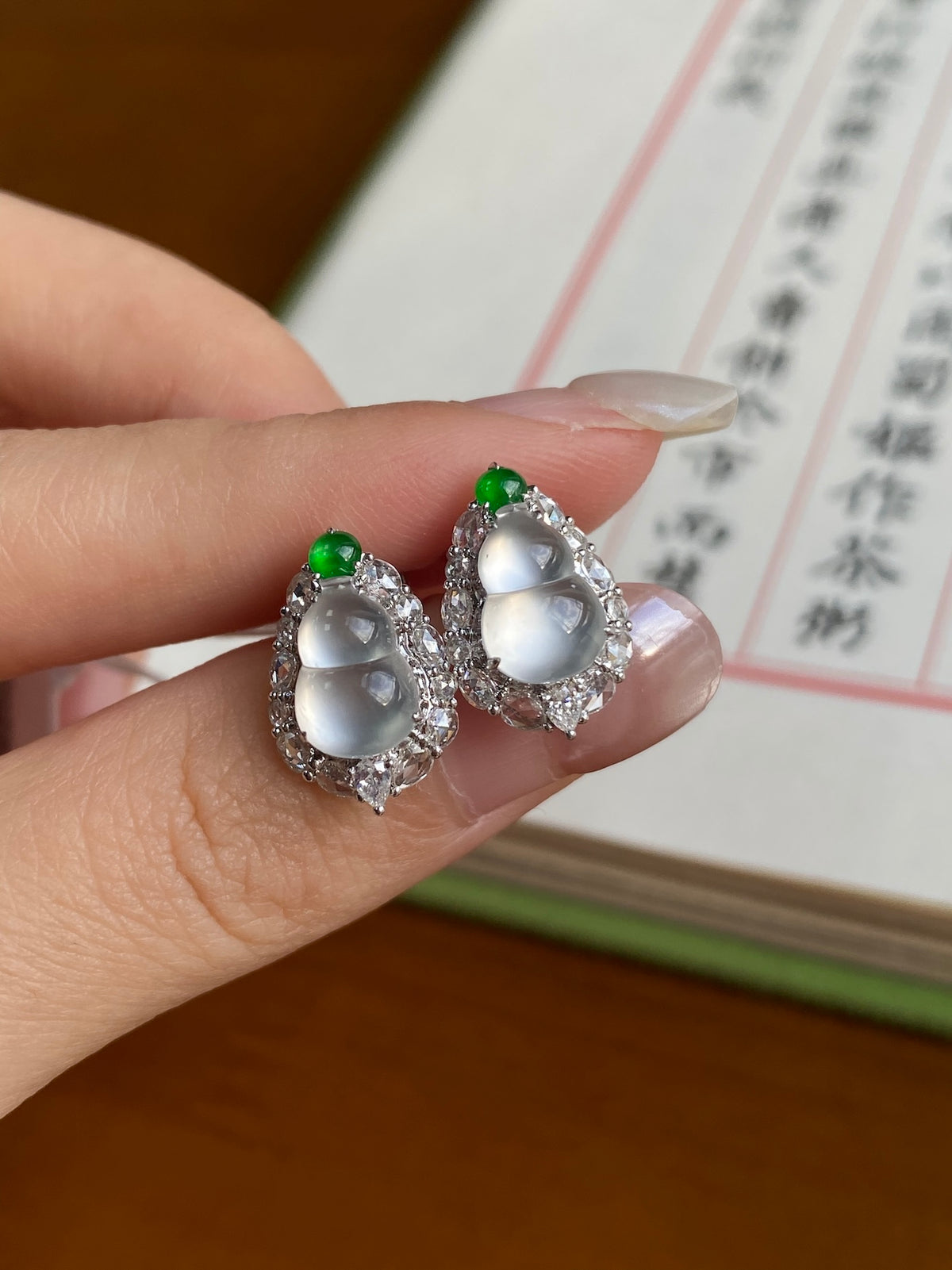Oval stud earrings with white cabochon, green tops, silver-tone halo setting