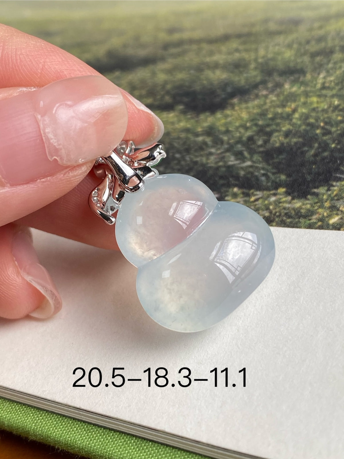 Close-up icy white jade gourd pendant with silver-tone setting, green leaf, clear stones