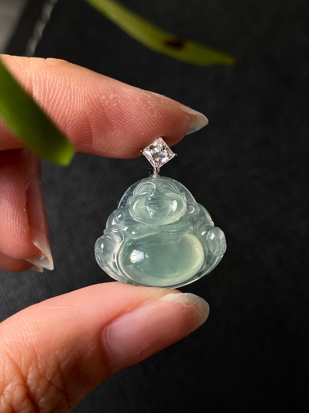 Green jadeite Laughing Buddha pendant angled view, silver bail and square clear top stone